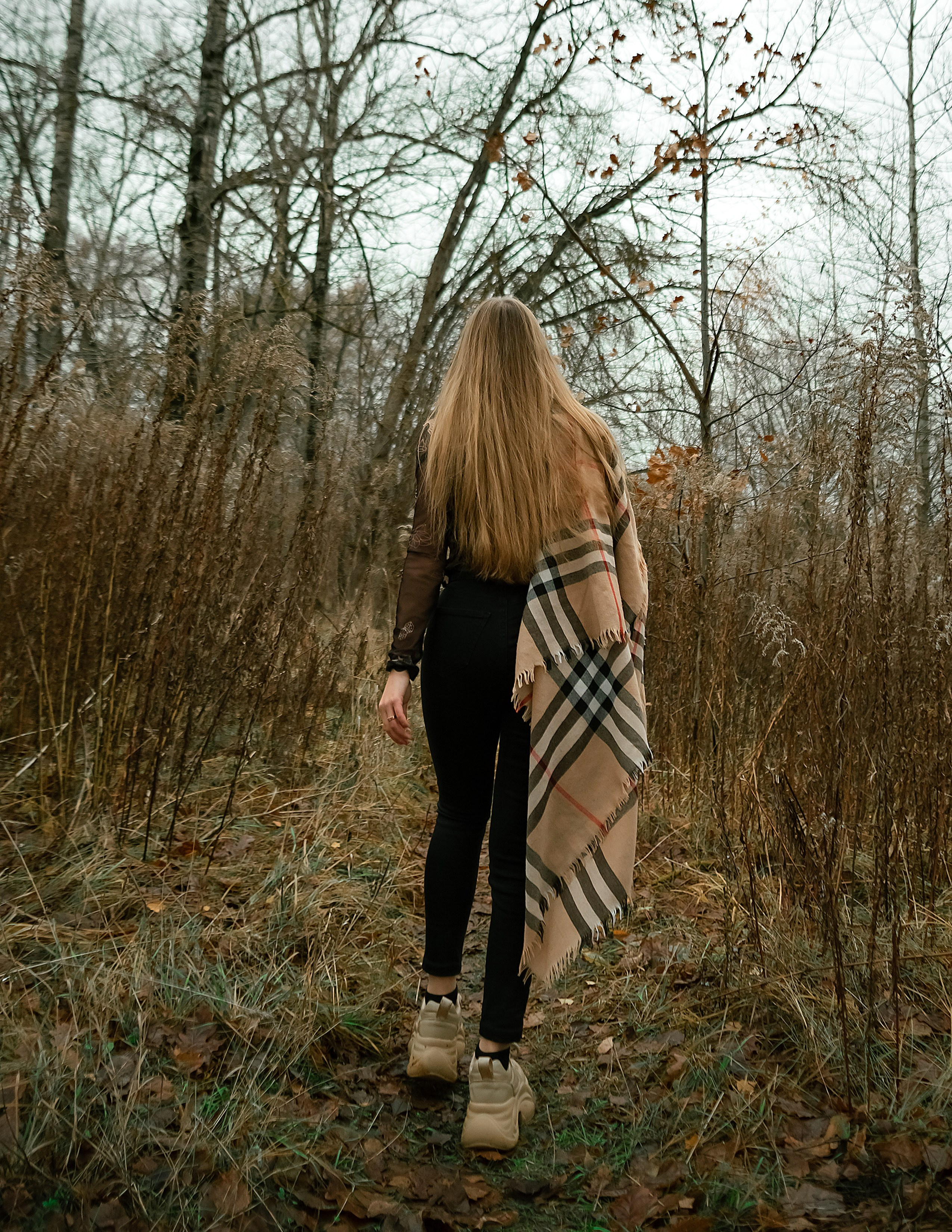 На фото девушка идет по осеннему лесу.