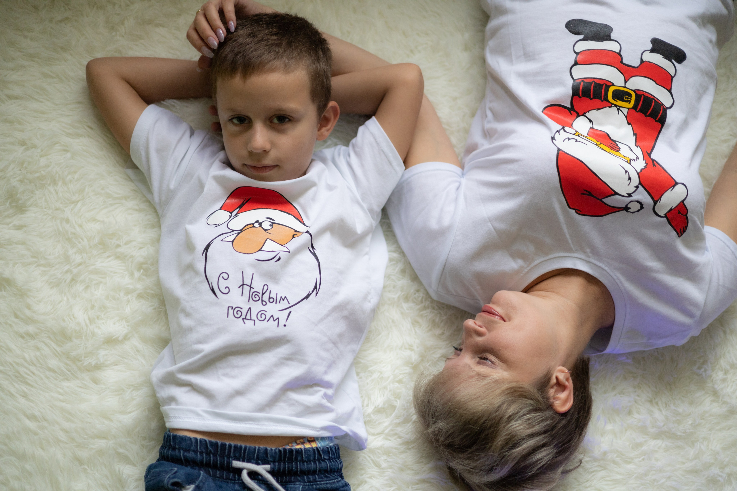 Мама с сыном лежат на пушистом белом ковре