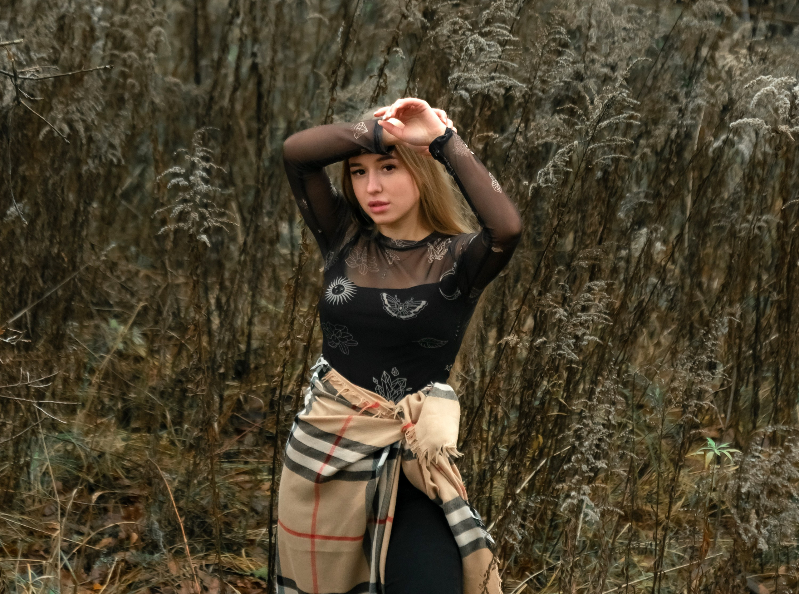 На фото девушка стоит в осенней траве.