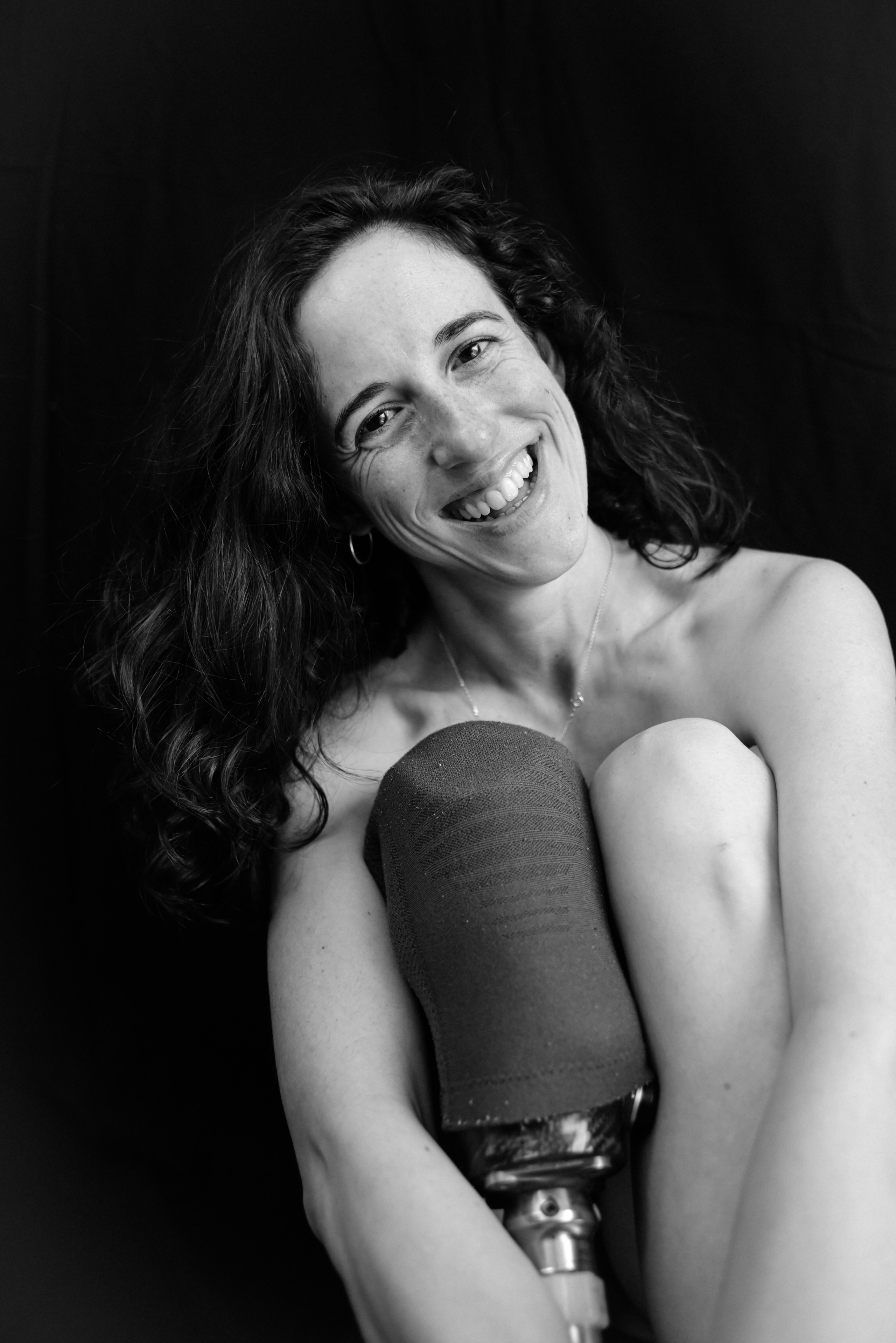 Boudoir photography London — black and white portrait of woman who had a cancer, she is smiling joyfully, natural and liberating expression