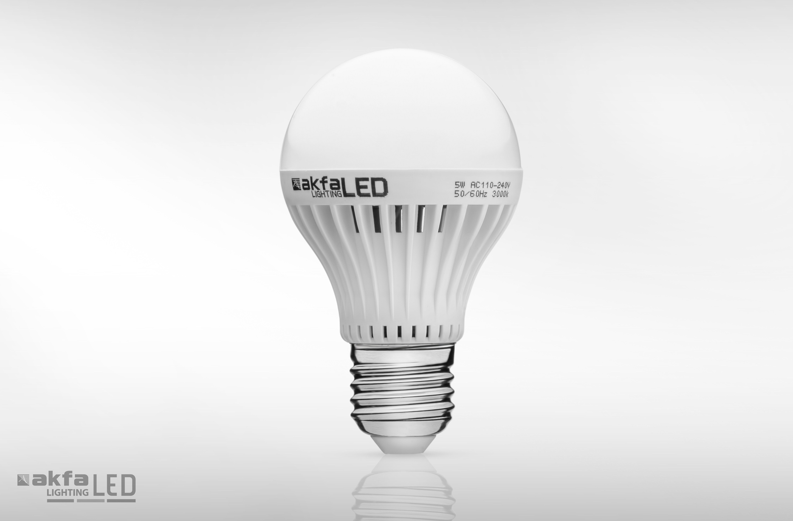 Каталожная фотография светодиодной лампы AKFA Lighting мощностью 5 Вт с цоколем E27 на белом фоне и мягким отражением