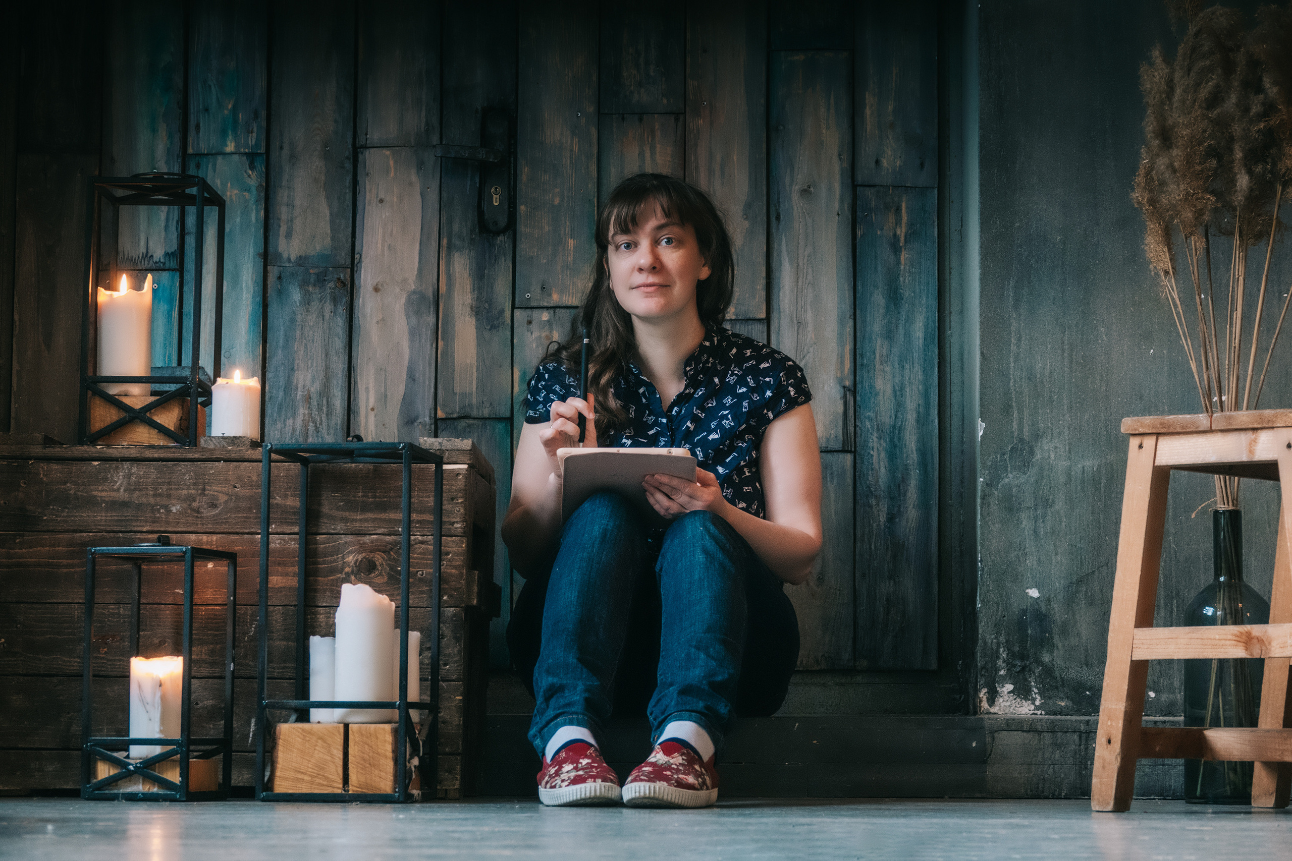 Девушка сидит на полу рисует при свечах смотрит в камеру