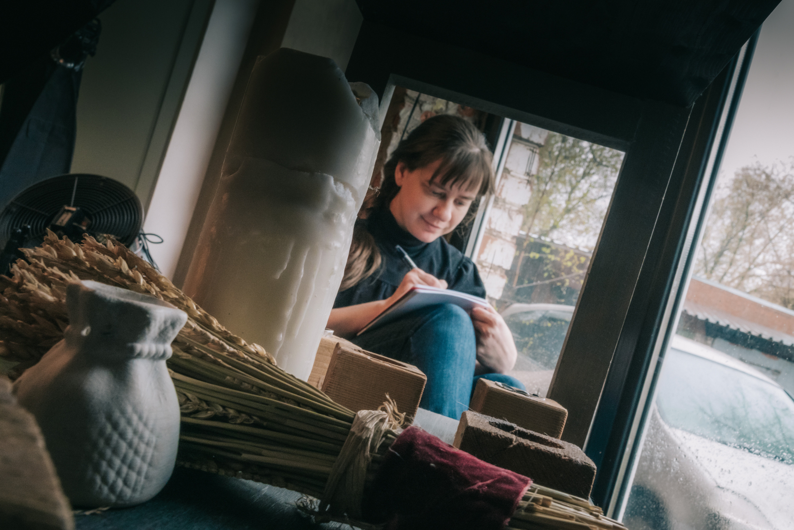 Девушка у окна сидит и рисует