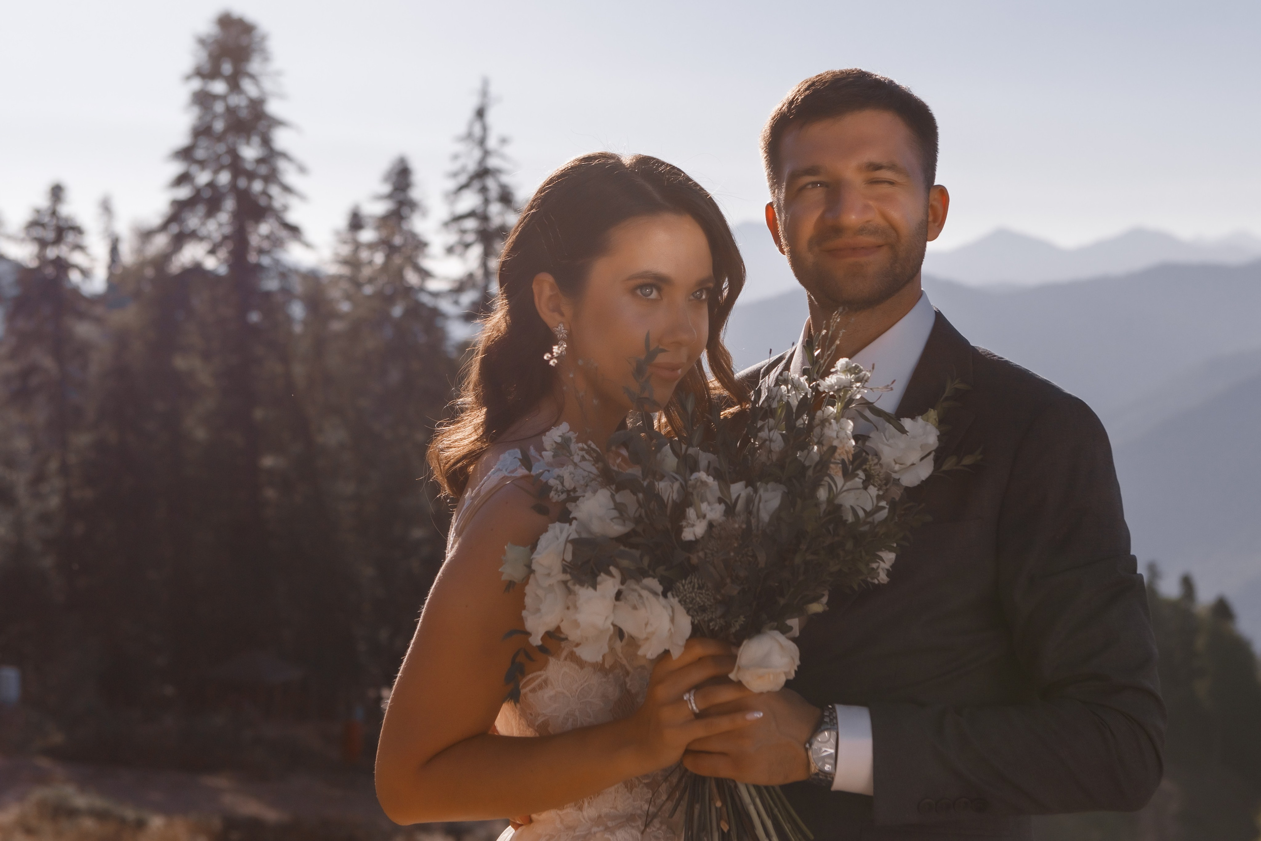 Жених обнимает невесту у горного озера в Полянах