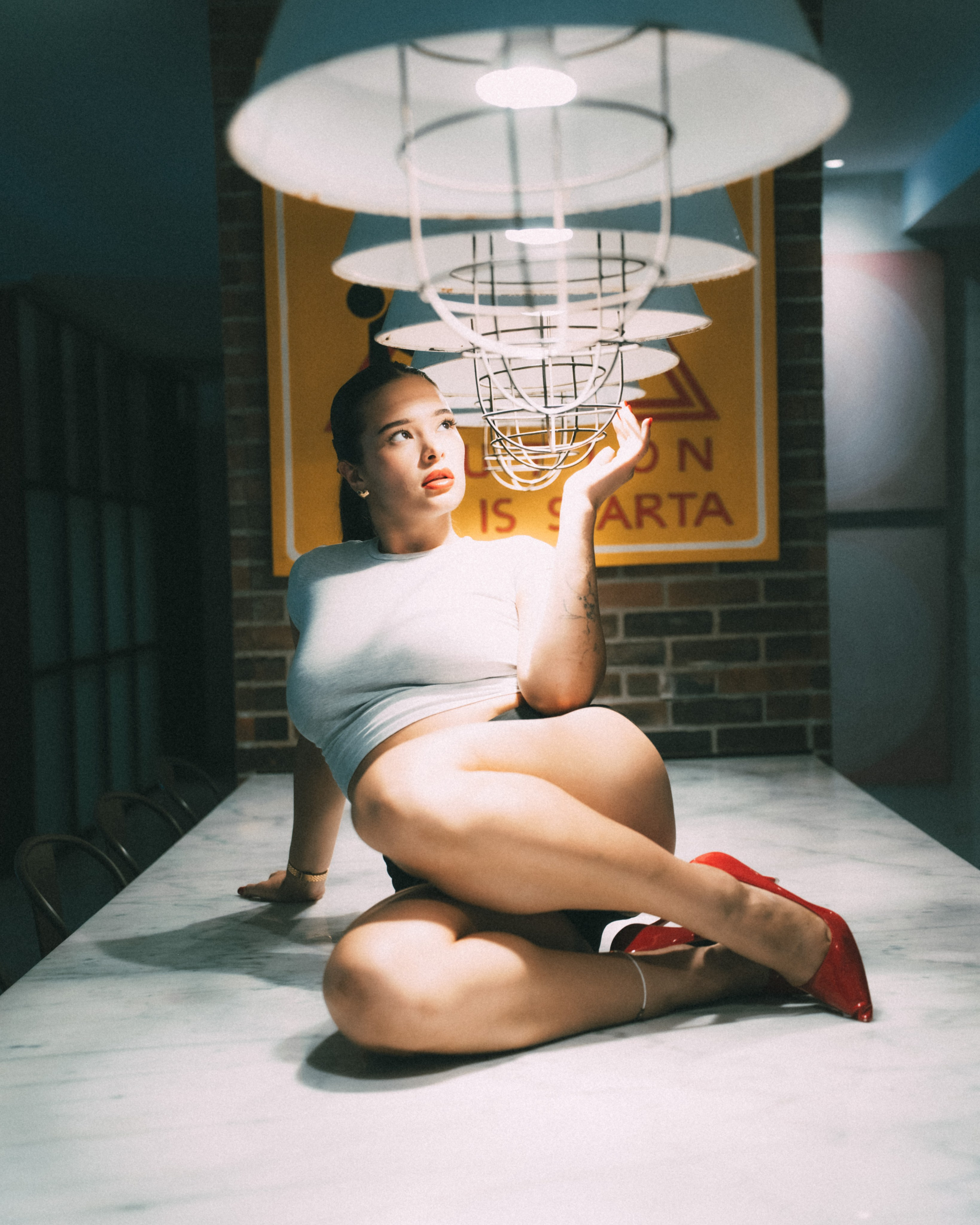 Фотосессия танцовщицы в шортах и красных туфлях на барном столе