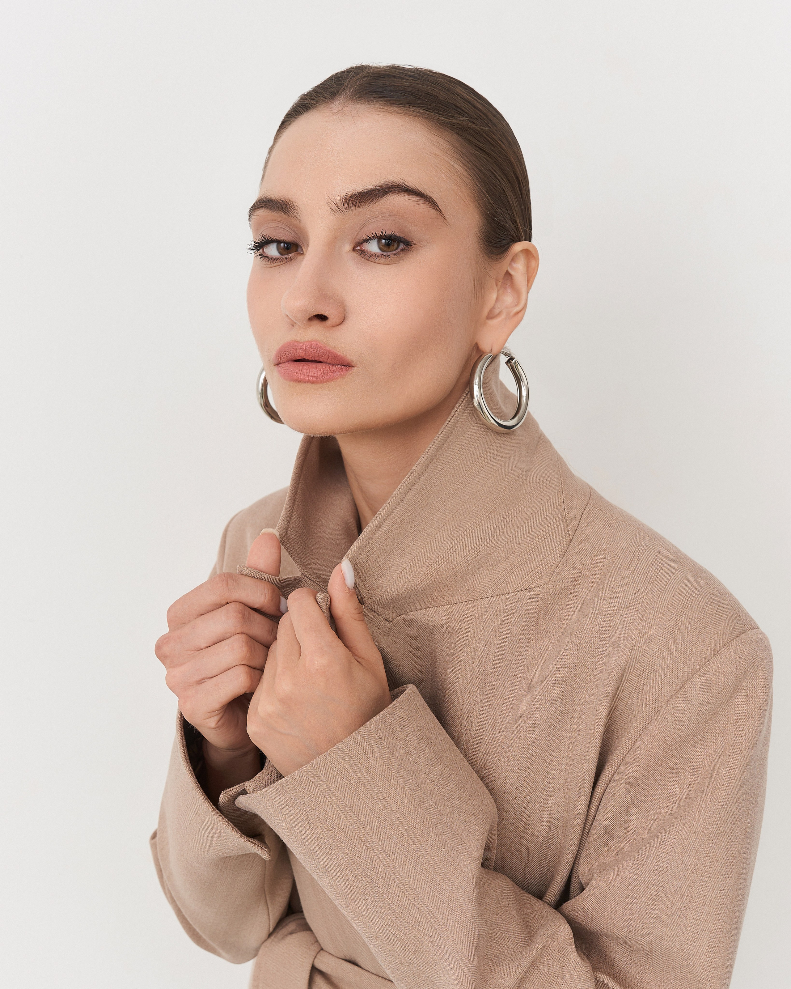 Пример коммерческой фотографии: крупный план бежевого пальто джемпера с детализацией ворота'