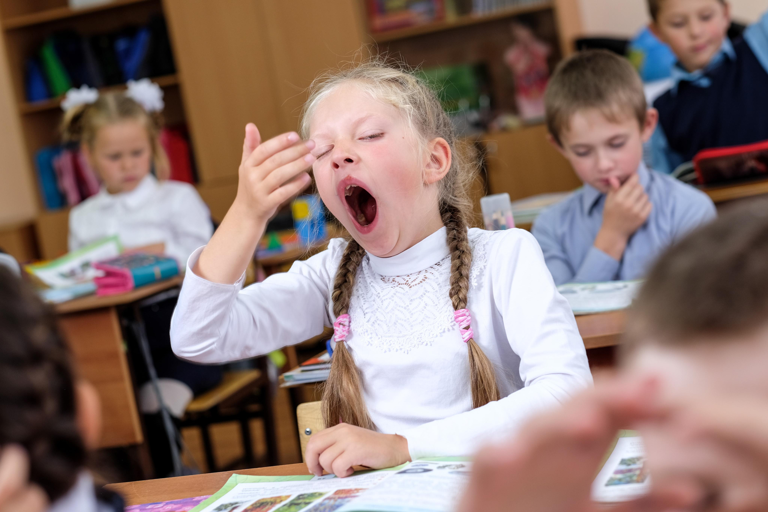 Девочка зевает на уроке