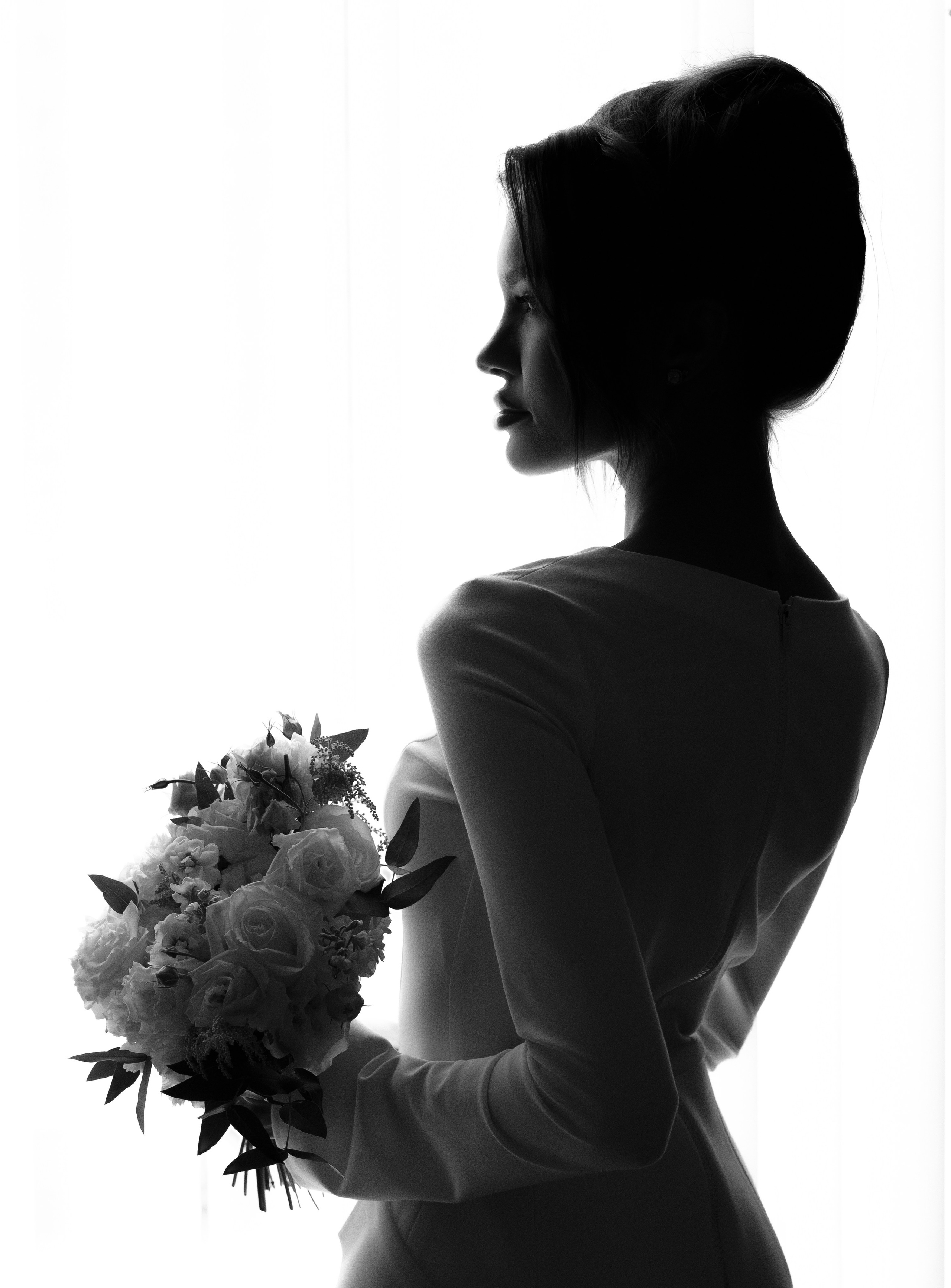 Невеста с букетом стоит у окна