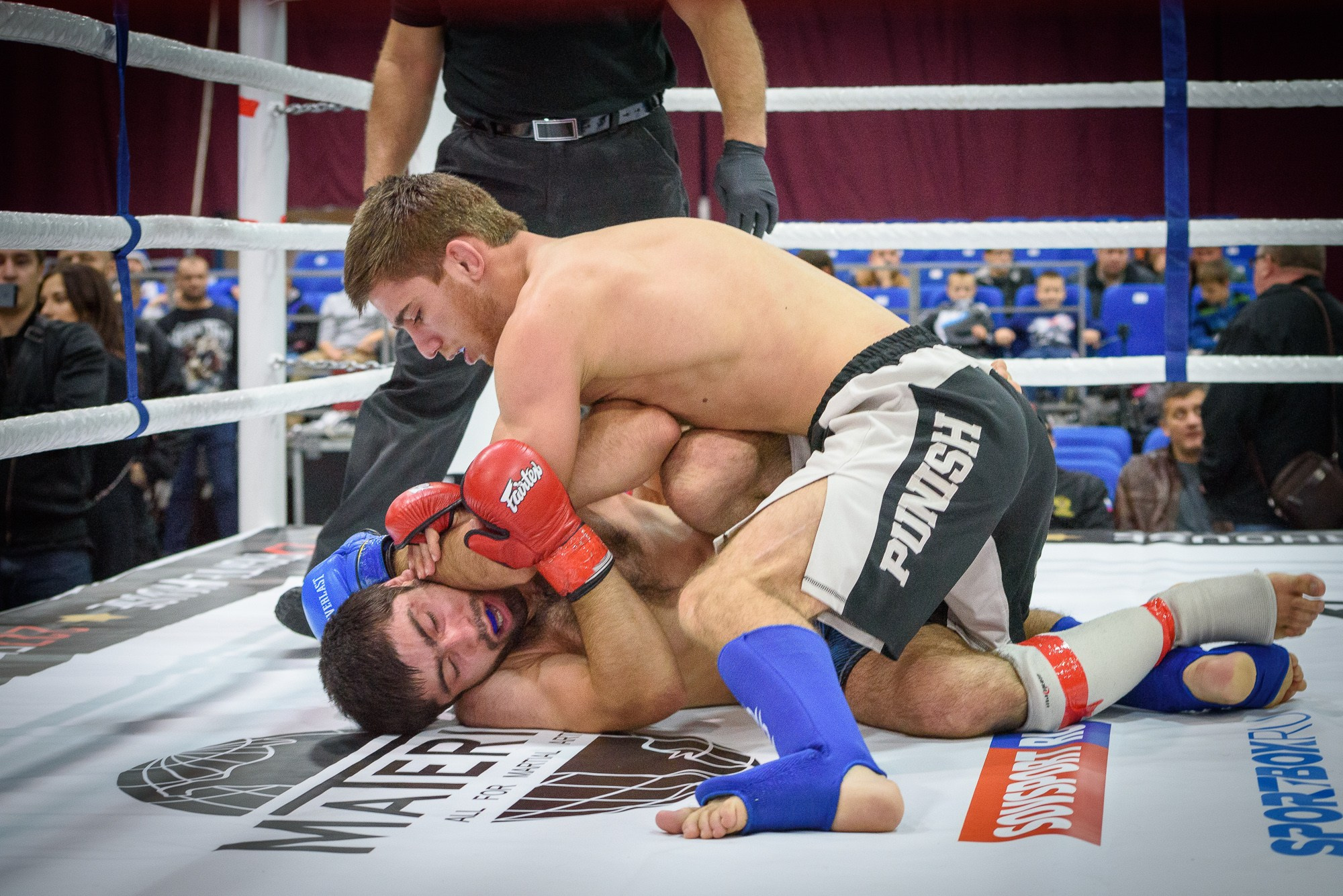 Боец ММА удерживает соперника на полу ринга