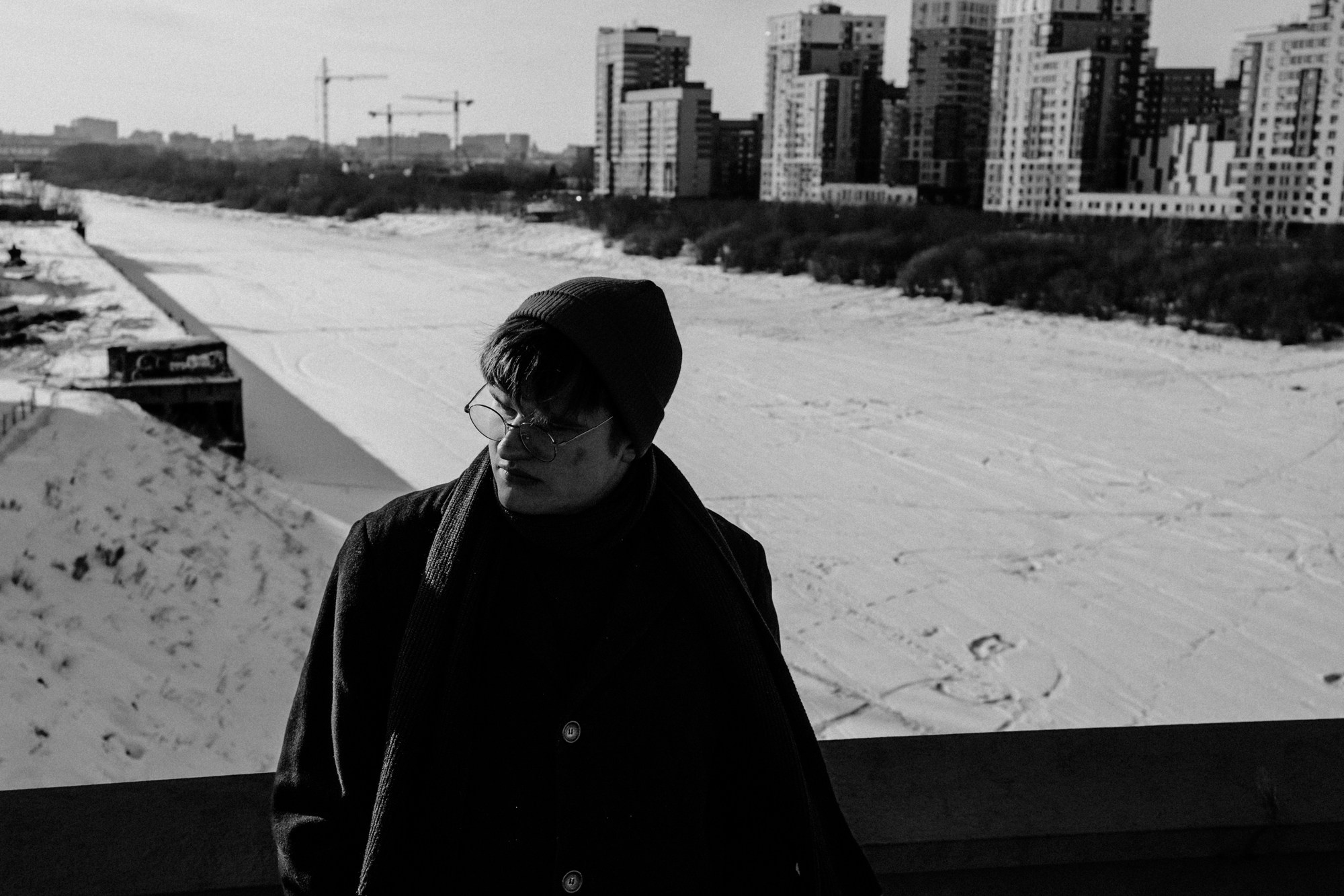 Парень в черном пальто на Набережной Тюмени, вид на Туру, мужская фотосессия