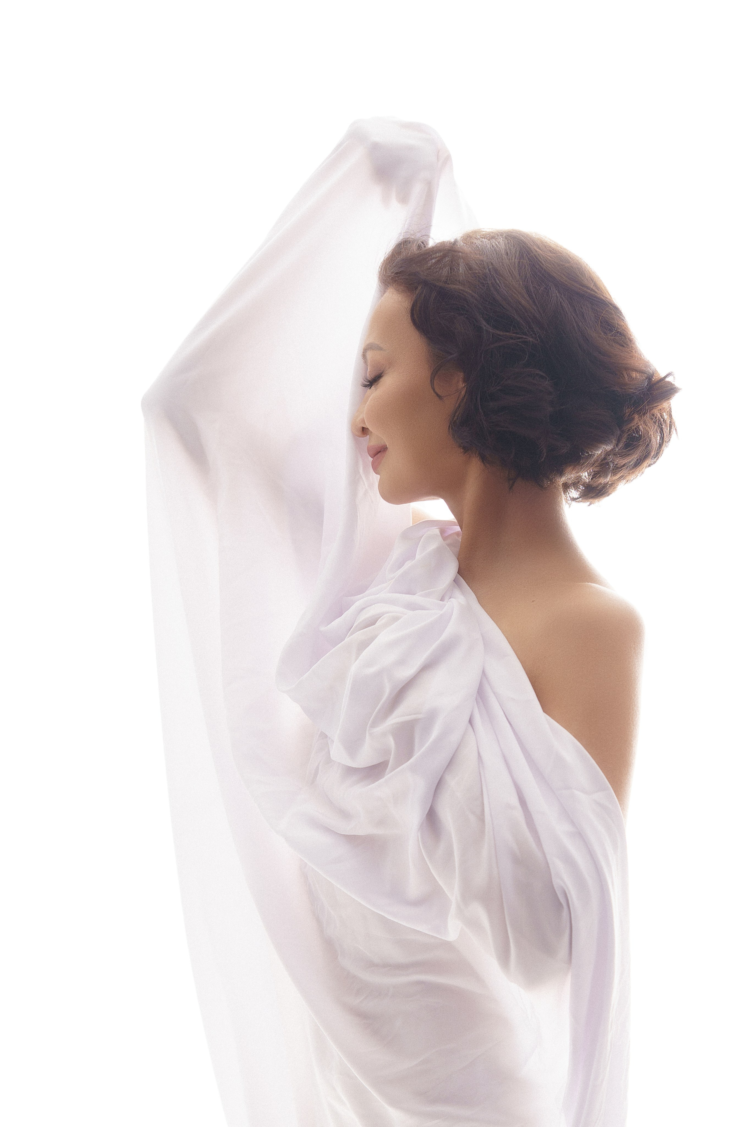 Будуар и ню фотография на которой женская фигура в ткани на белом фоне в стиле минимализма при мягком свете