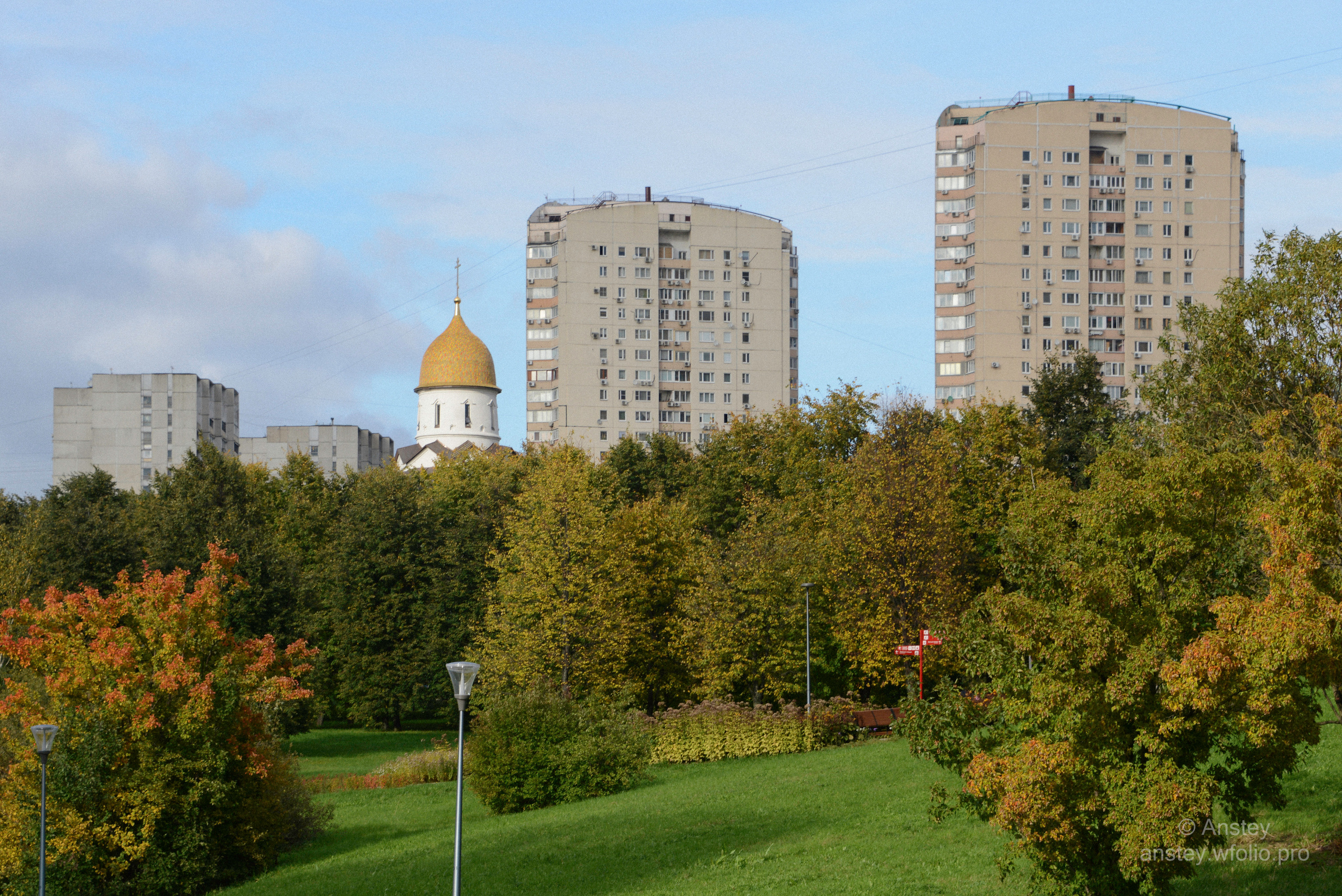Trees and buildings in Moscow city against blue sky. Travel in a park in early autumn season.
