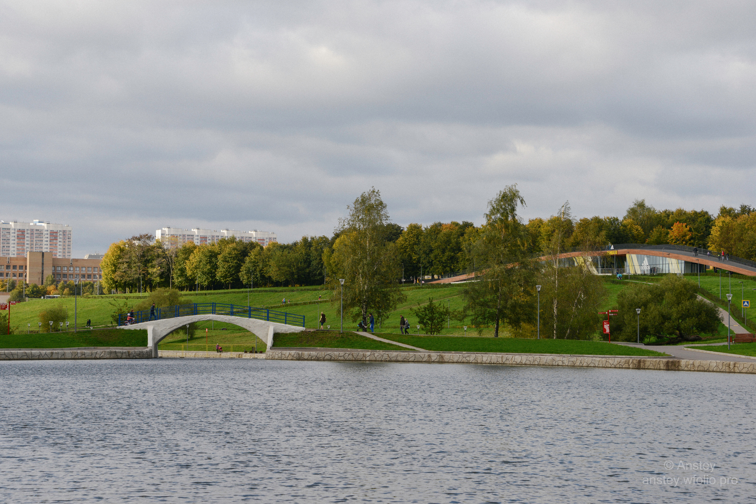 Олимпийские пруды. Scenic view of Moscow city park with pond and buildings against sky in early autumn.