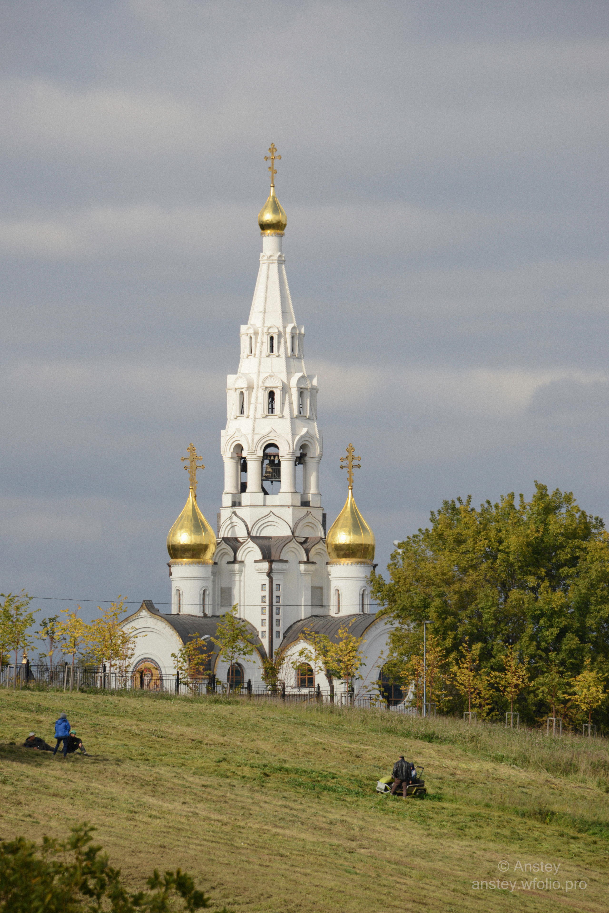 Low angle view of Russian Orthodox Christian church on green field against cloudy sky.
