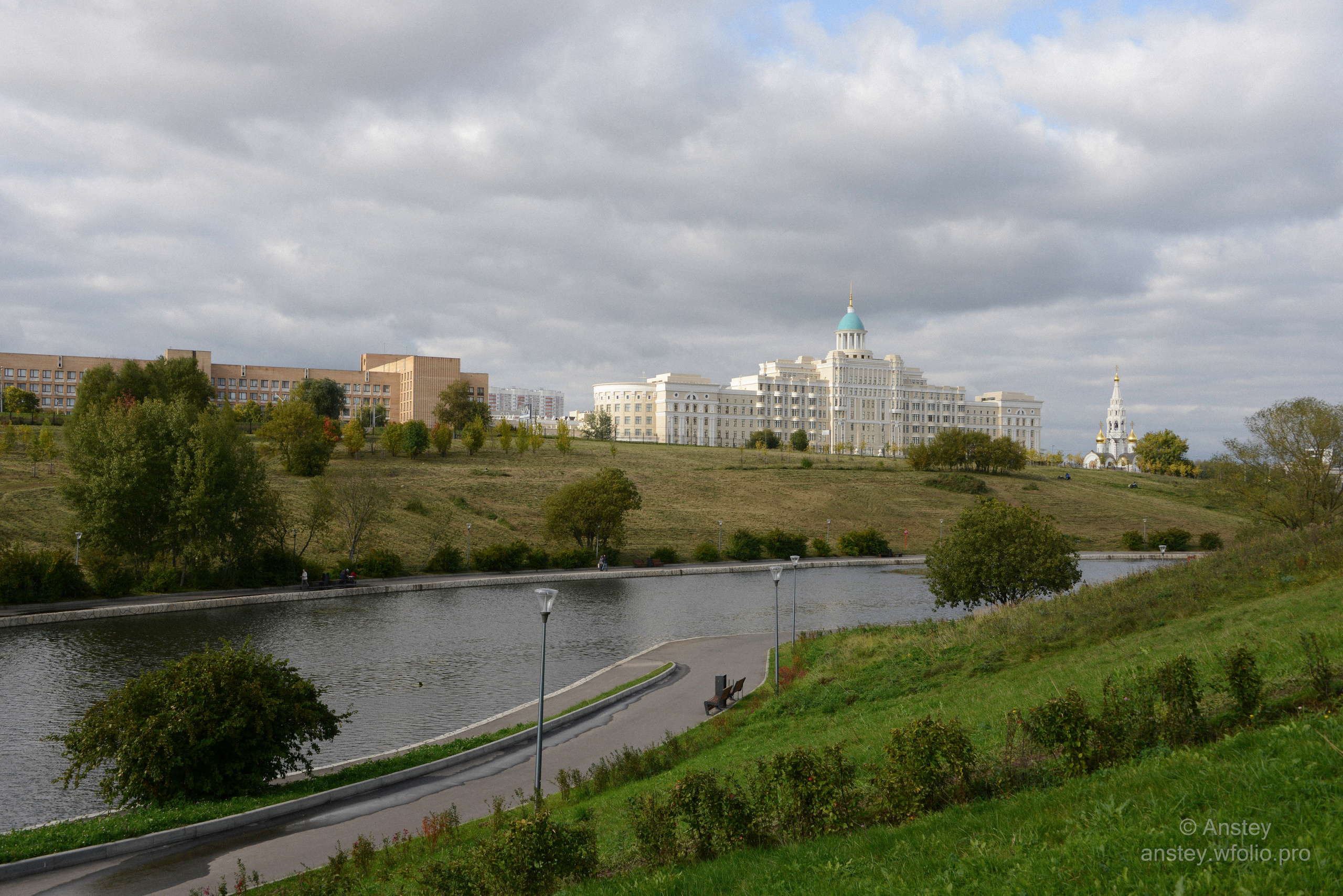 Вид издали на пруд и здание Академии Федеральной службы безопасности Российской Федерации из парка Олимпийской деревни на западе Москвы.