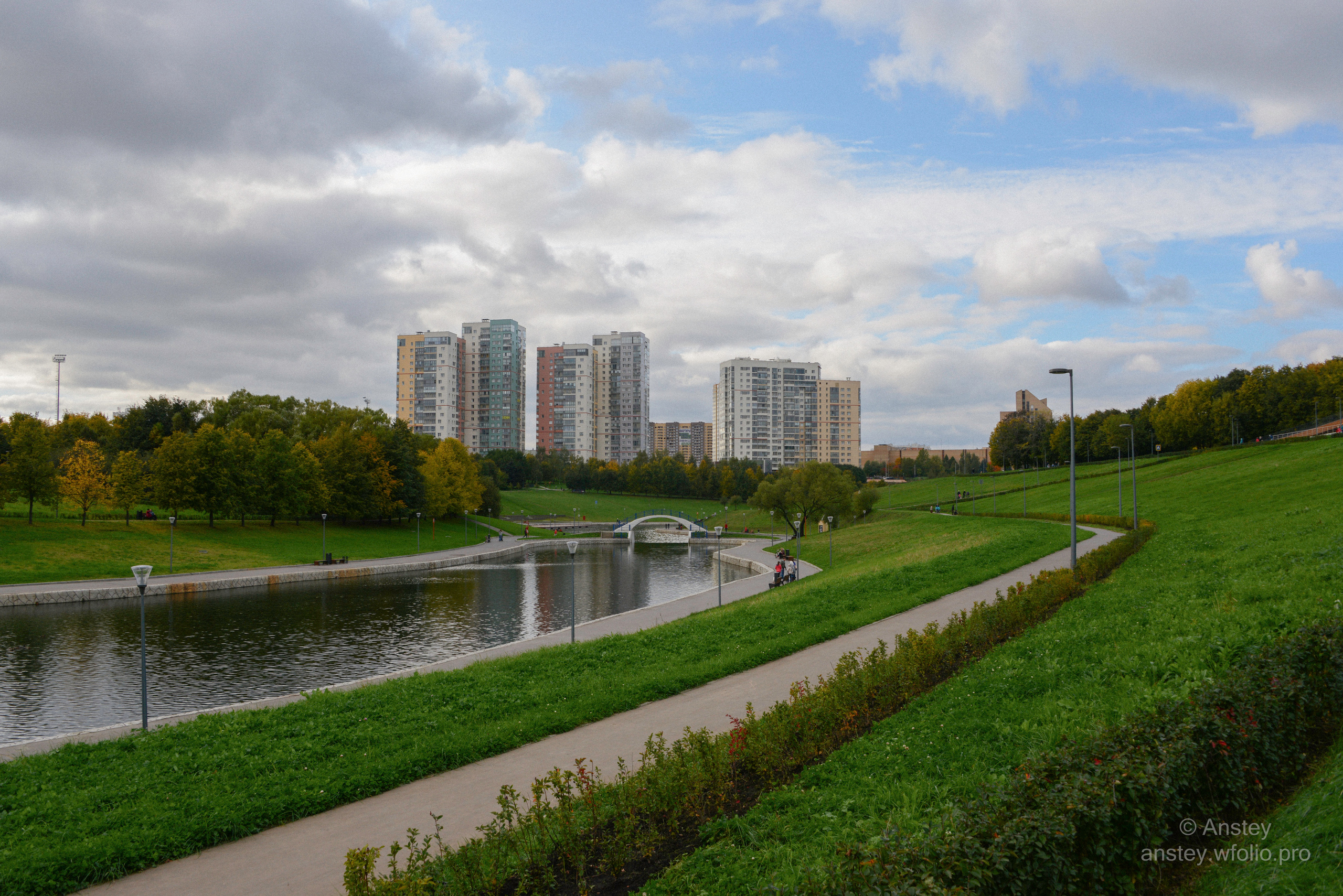 Парк Олимпийской деревни в Москве ранней осенью в сентябре. Scenic view of a pond against sky in a Moscow city park in early autumn season.