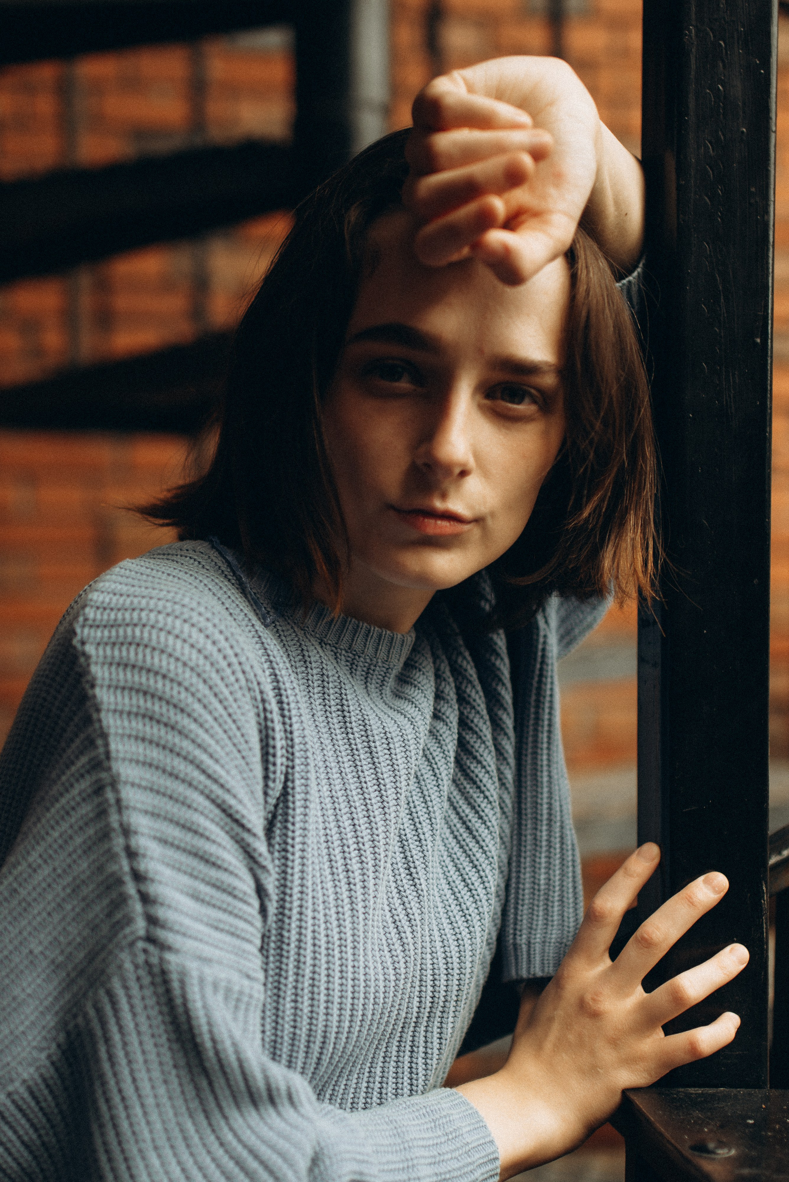 Девушка в голубом свитере на фоне кирпичной стены и черной винтовой лестницы, портретная фотосессия в индустриальном стиле. Фотосессия в Новосибирске. 1.