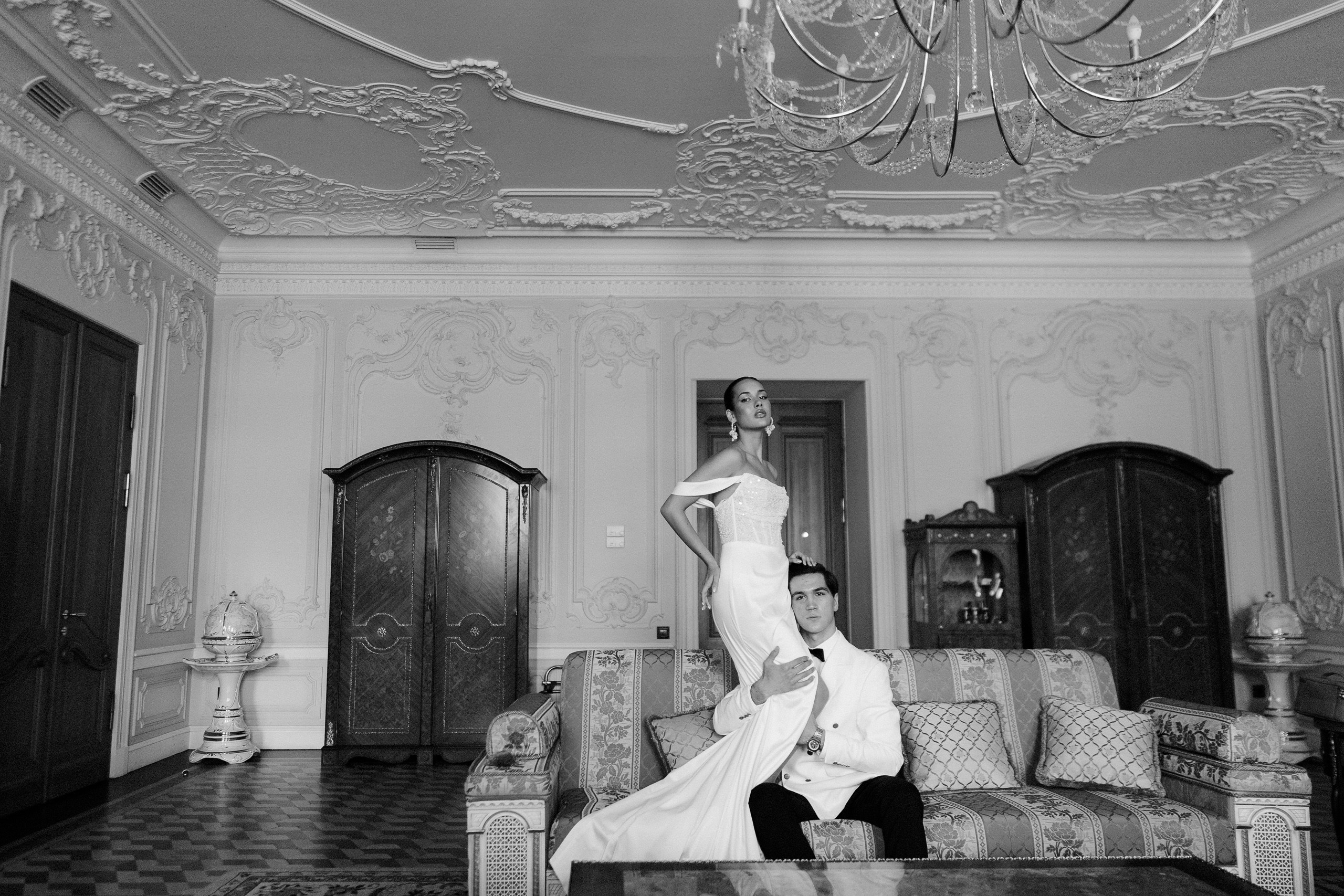 Чёрно-белый кадр: пара в зале с антикварной мебелью и люстрой — свадебная съёмка в Trezzini Palace Hotel, Санкт-Петербург