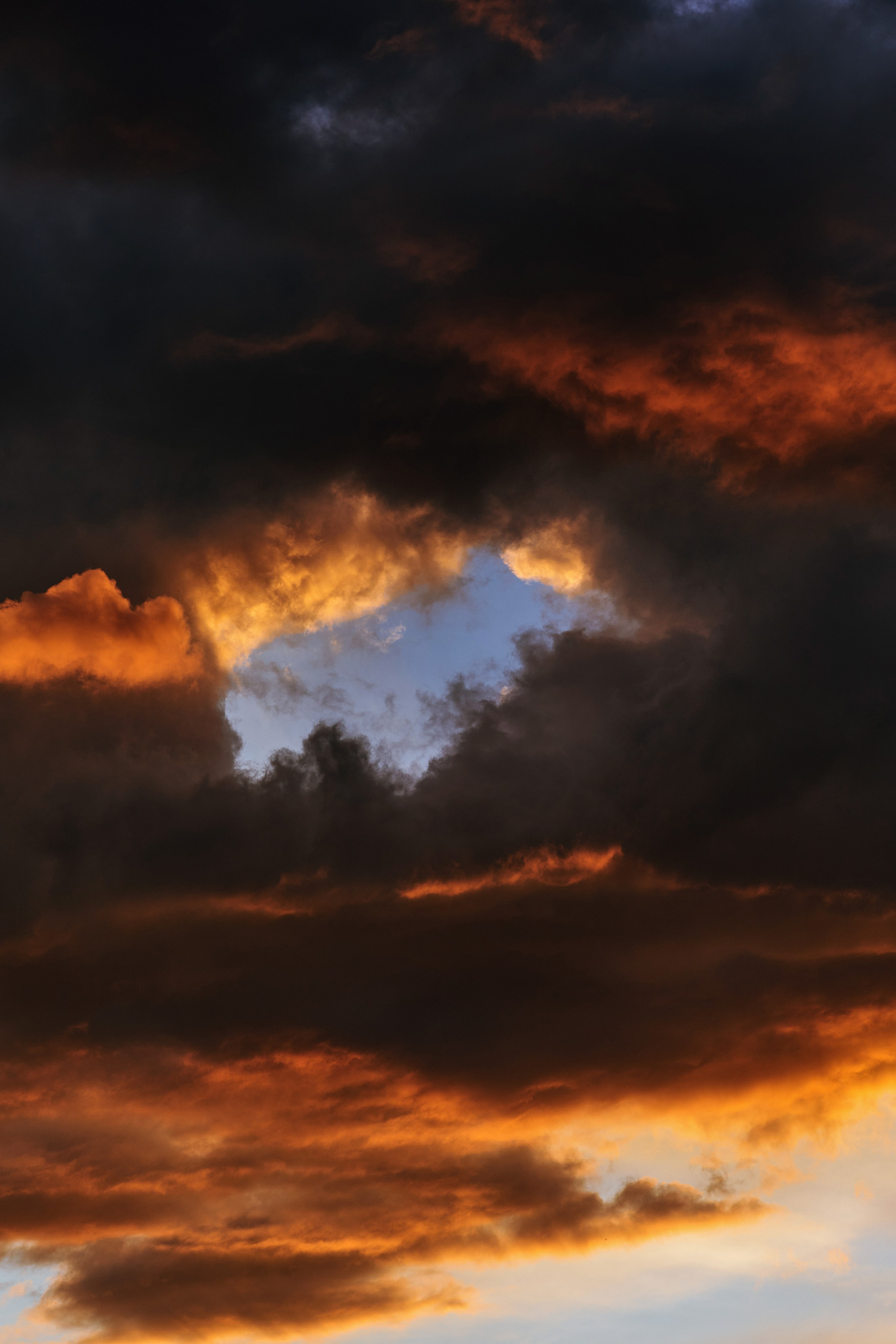 Огненный закат с красно-оранжевыми облаками, вертикальная фотография