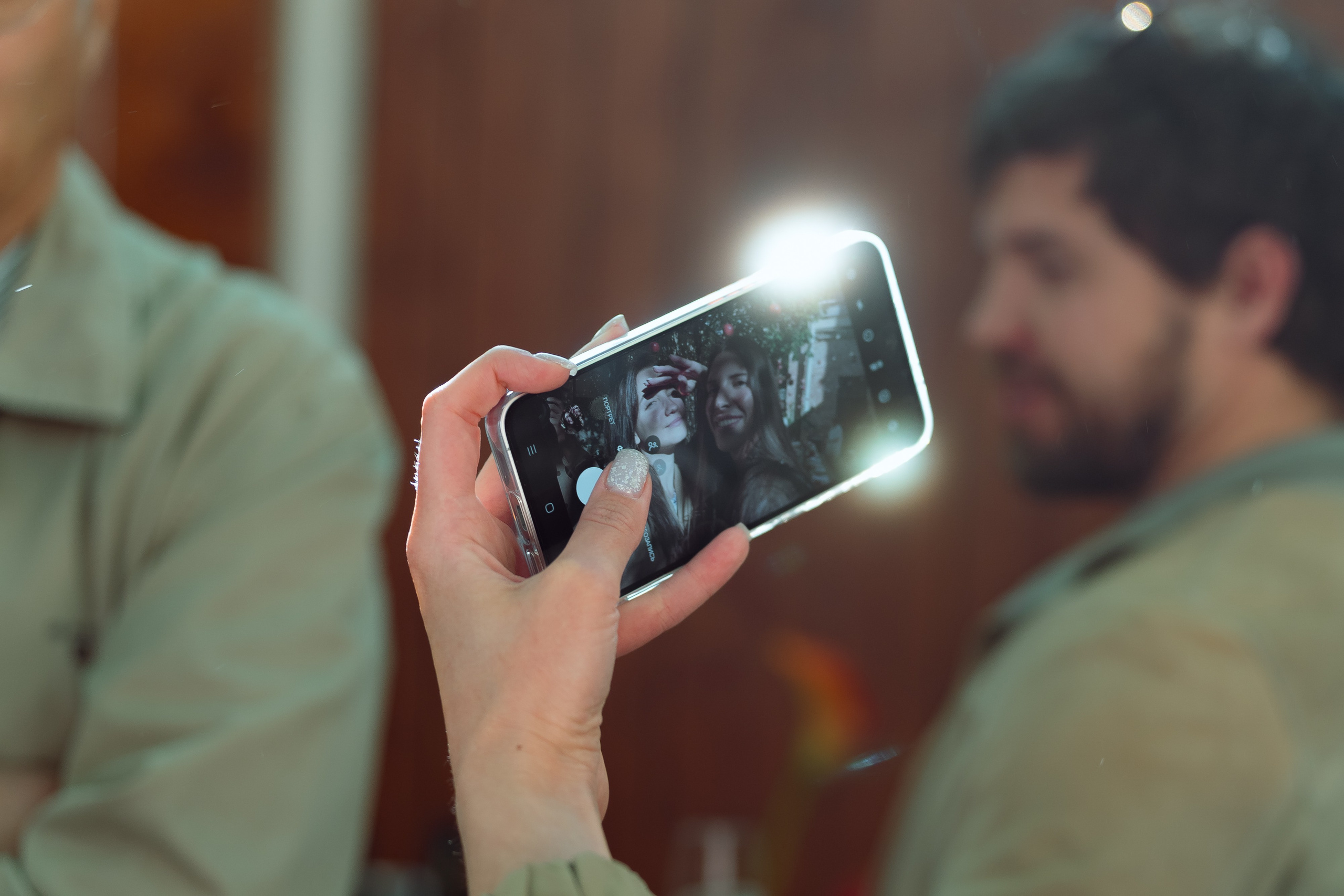 Рука гостя снимает видео на смартфон, солнце бликует в объективе