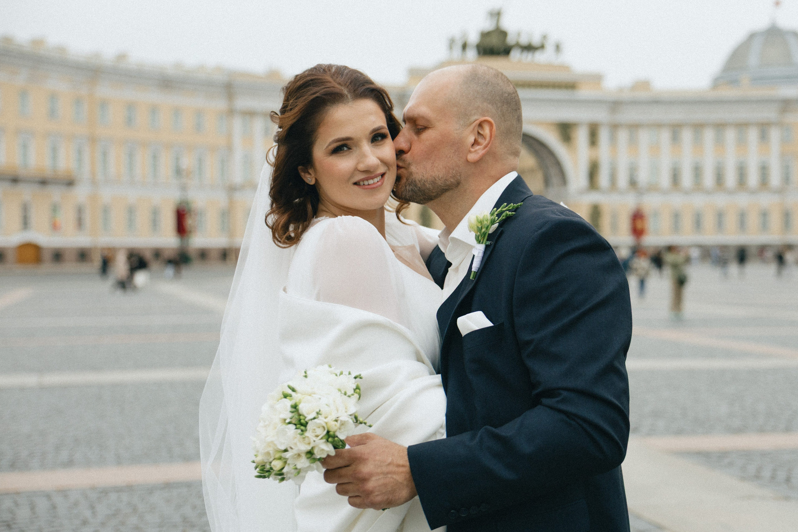 Свадебная фотосессия на Дворцовой площади в СПб, жених обнимает невесту на