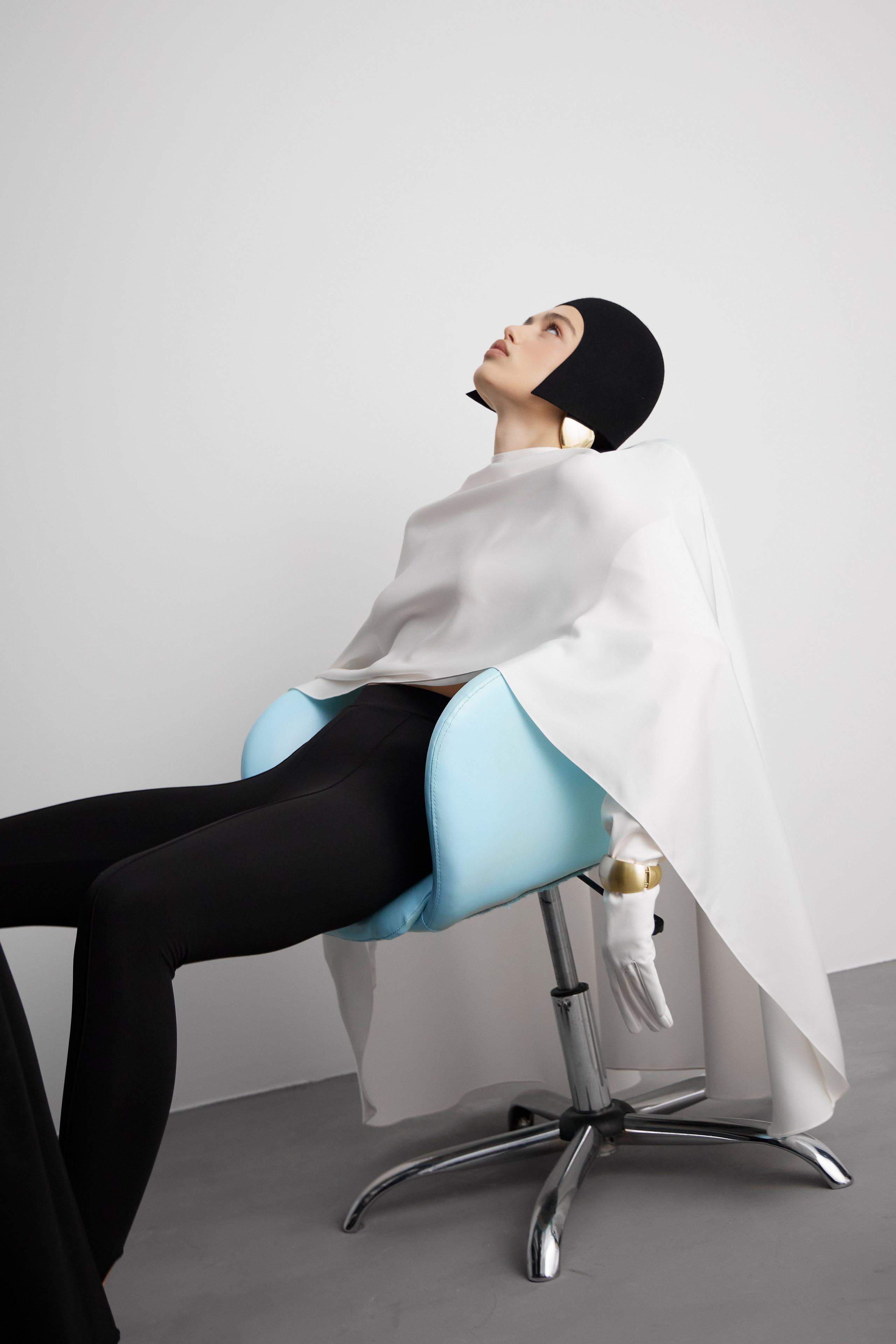 Editorial fashion campaign image of model reclining on chair in modern minimalist studio photographed for designer brand campaign in Sydney
