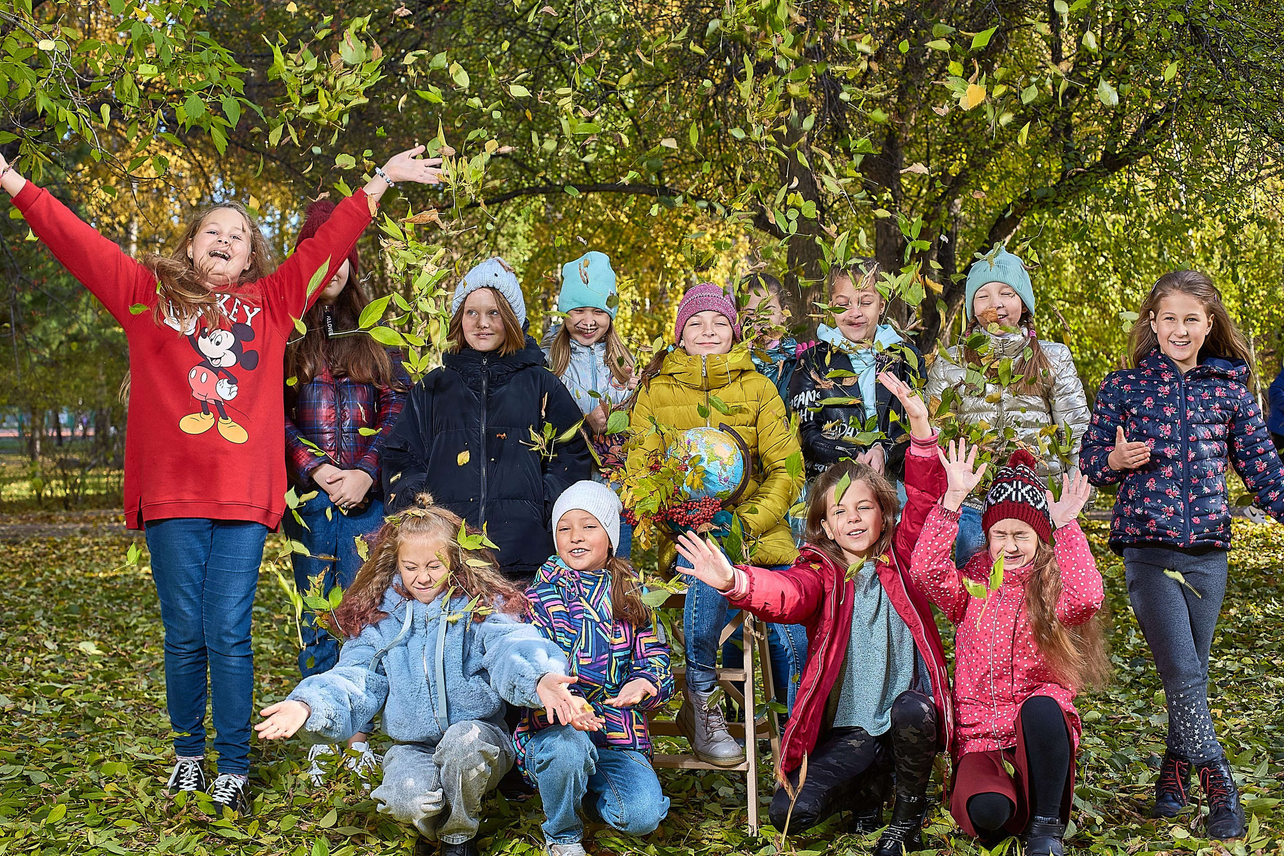 Ребята, выпускники - резвятся в парке, кидают листья.