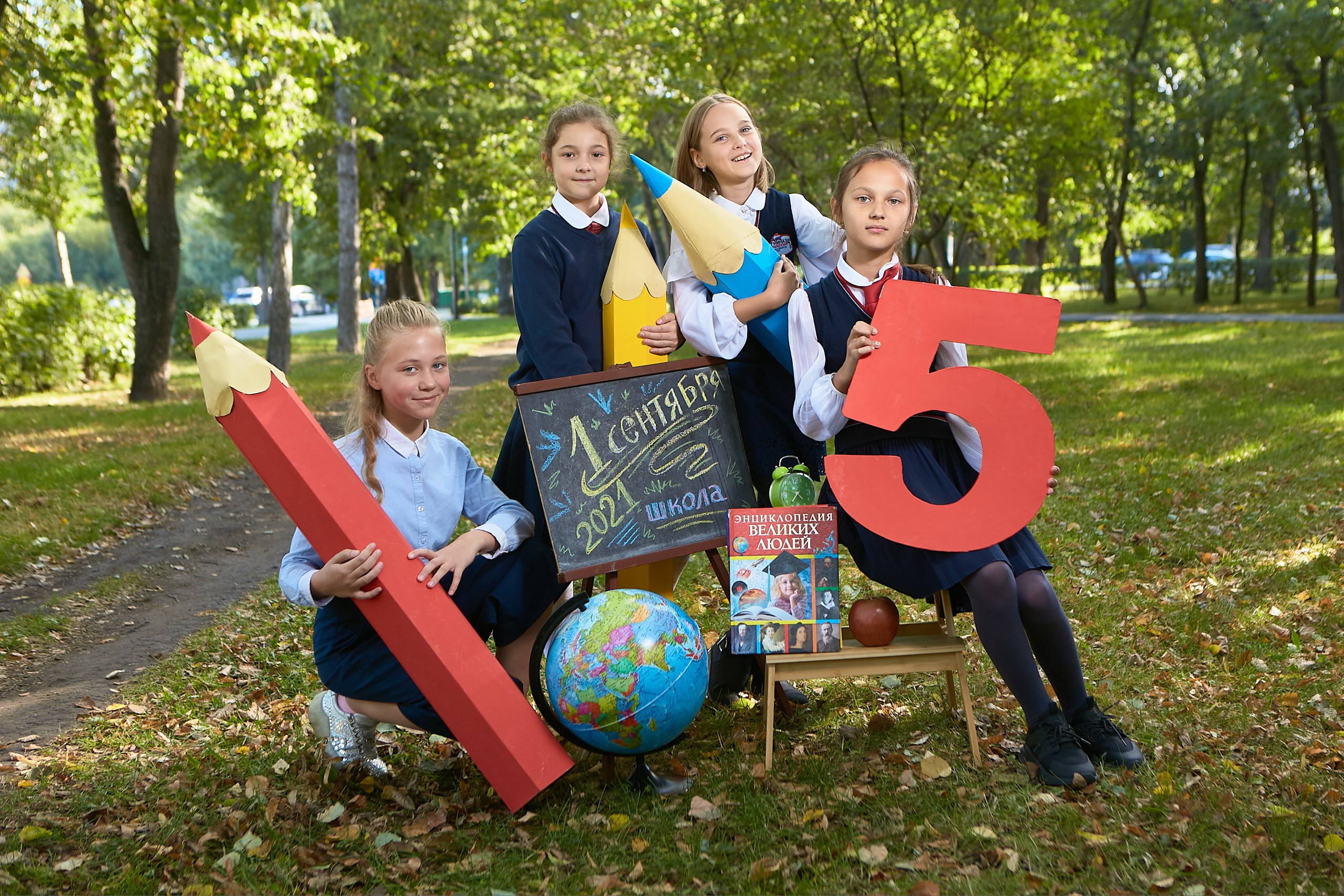 Школьные подружки фотографируются вместе в парке для фотокниги в четвертом классе