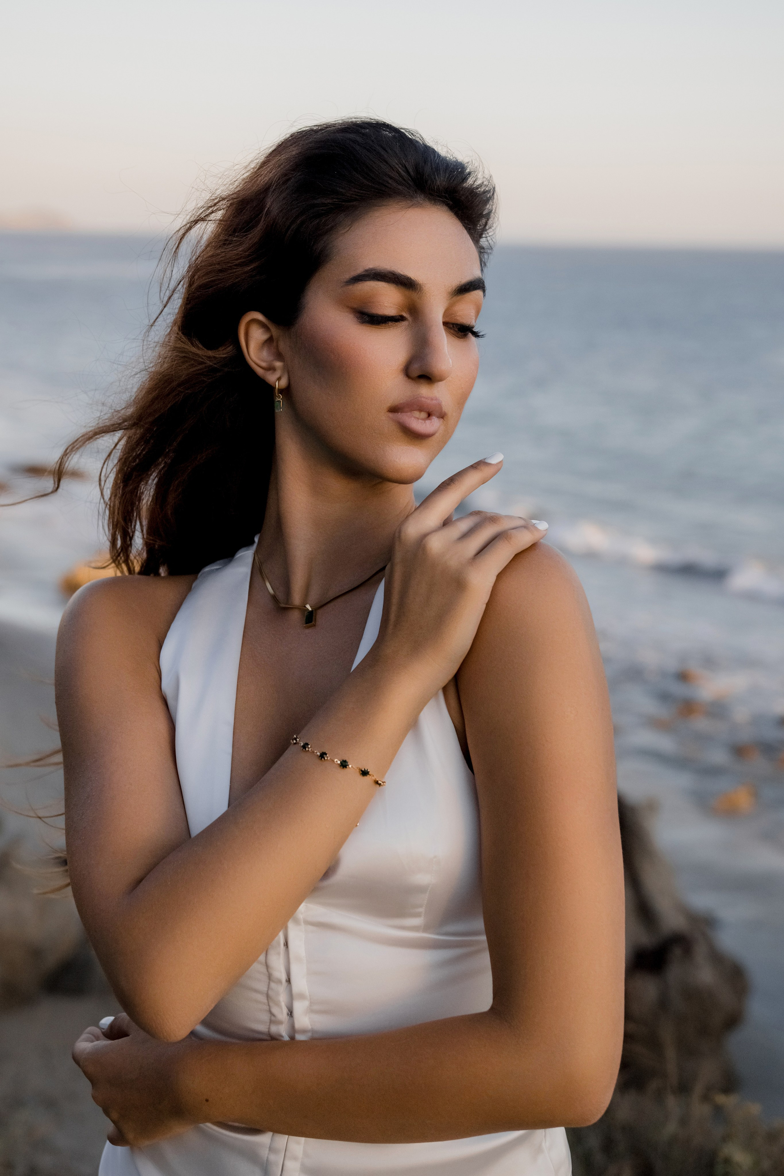 Close-up of a female model’s expression while standing by the ocean, showcasing calm and sophistication.