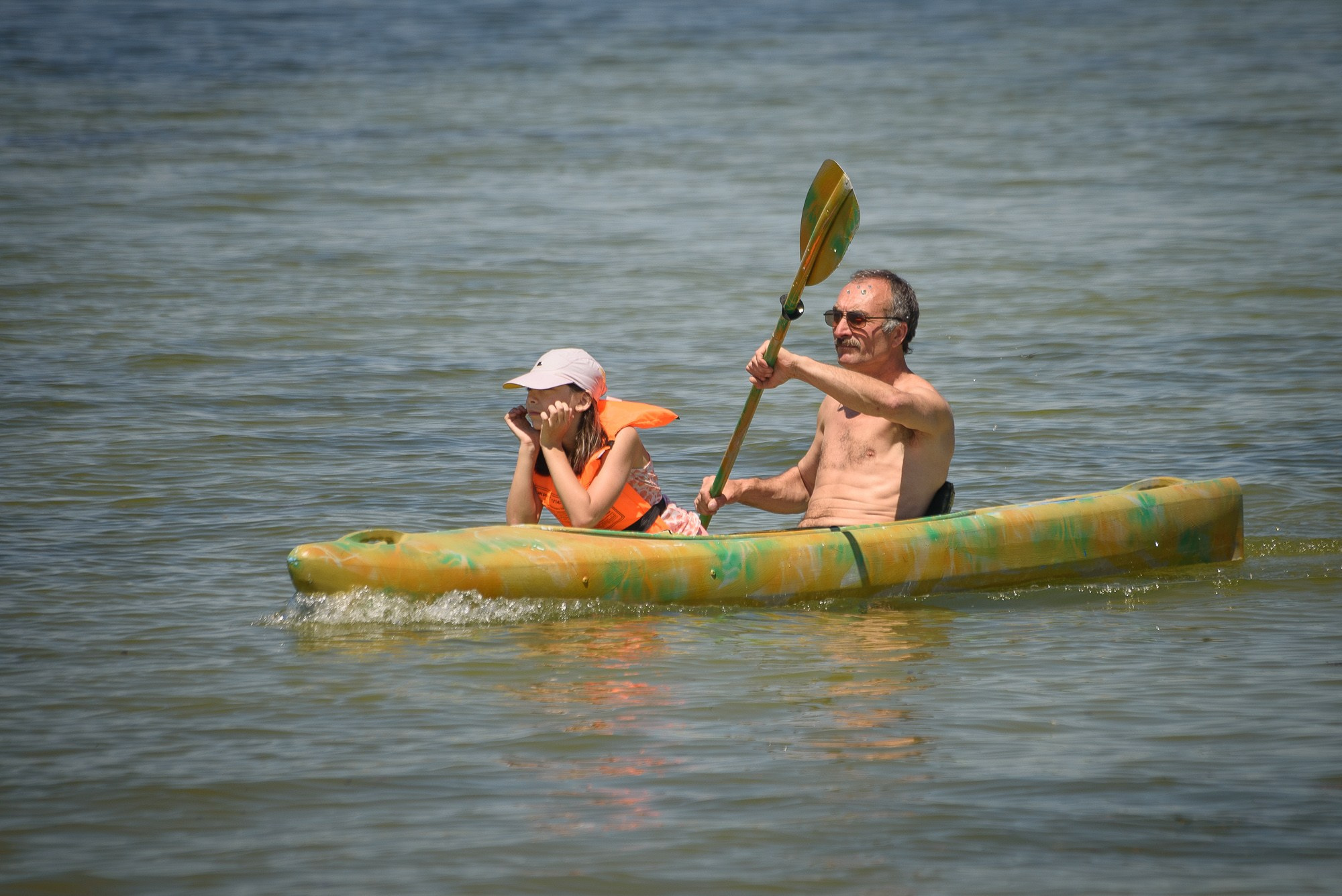Мужчина и девочка на байдарке в воде