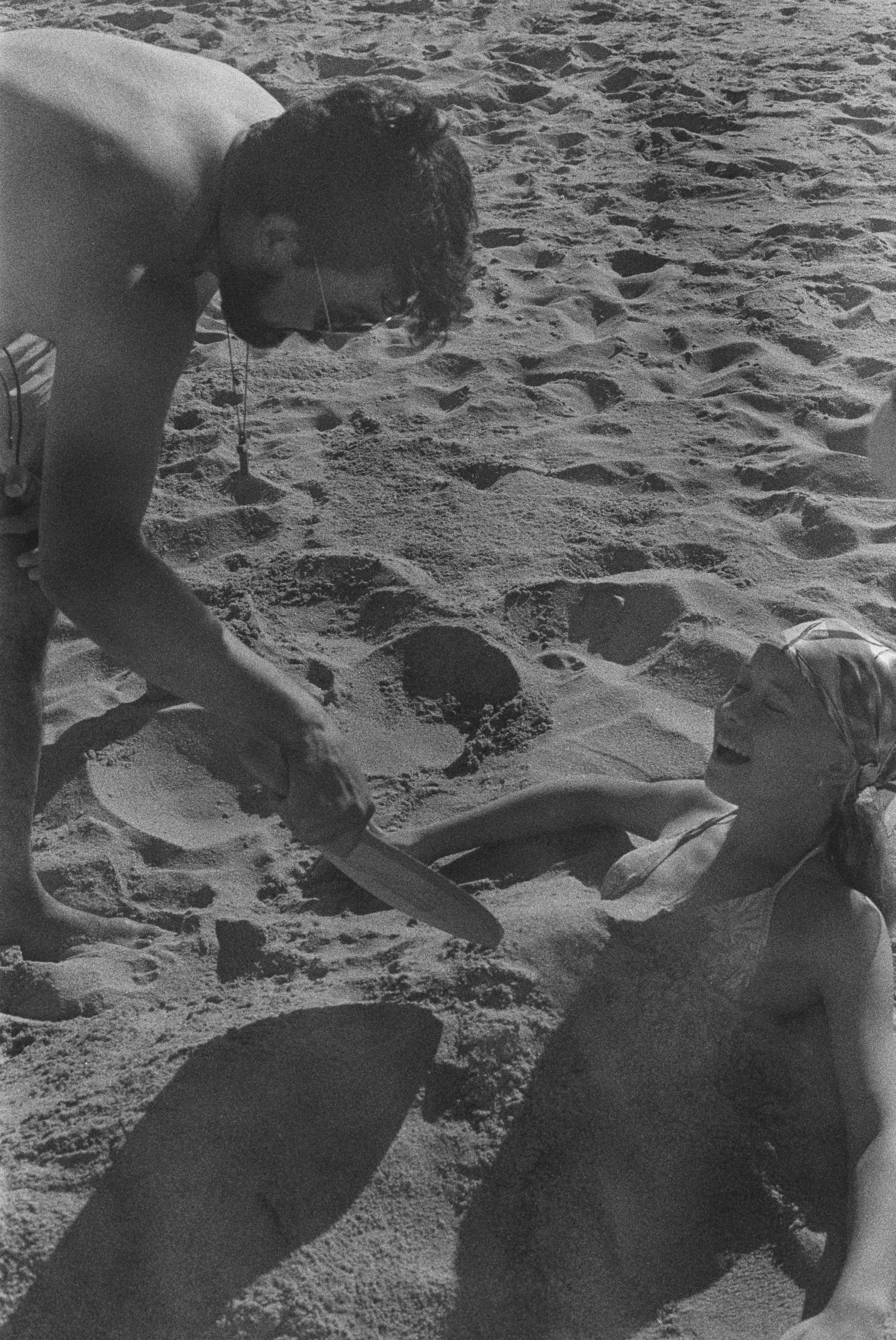 stepdaughter and father playing with the sand on the beach