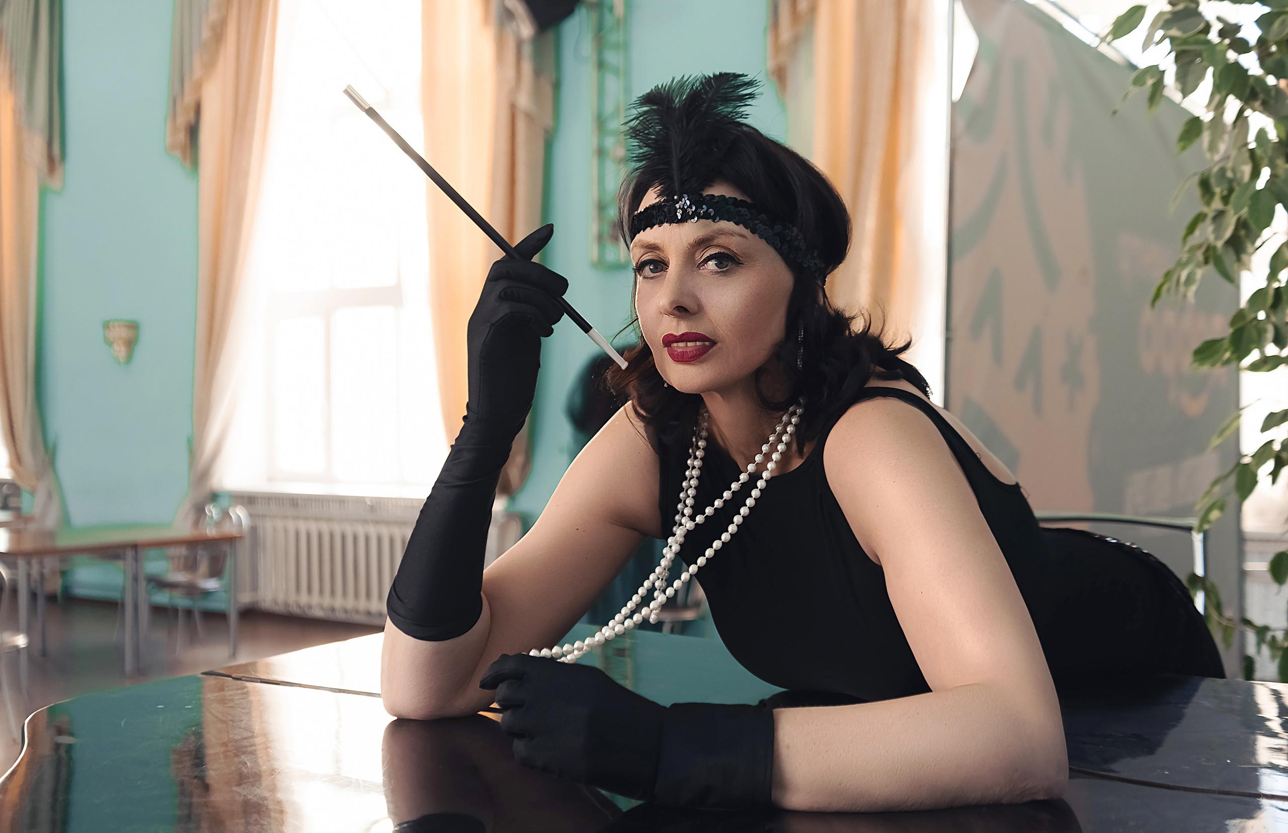 Девушка в стиле ретро, винтаж, Гэтсби около рояля смотрит в сторону.