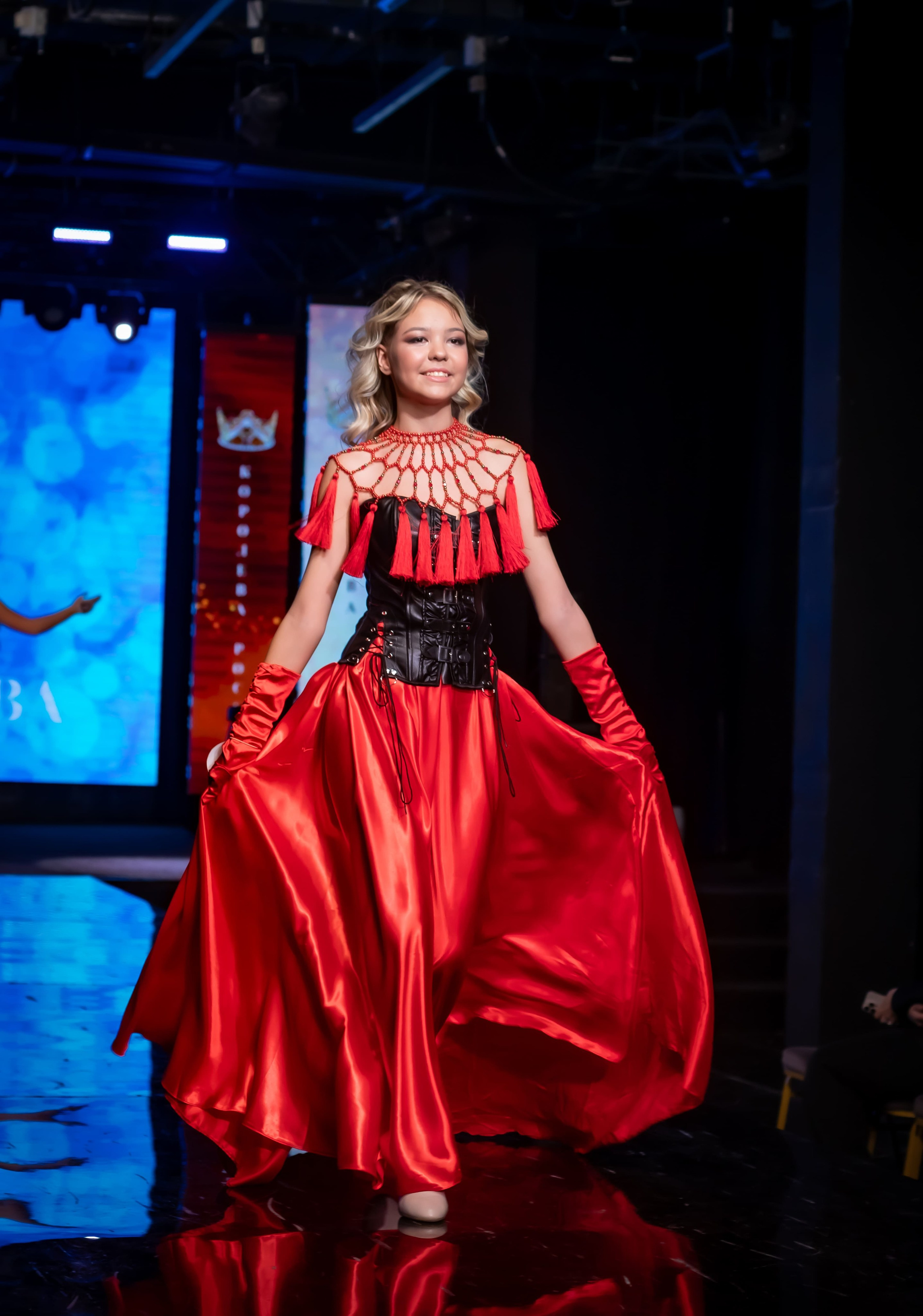 Модель в красном вечернем платье на подиуме, показ дизайнерской коллекции, Москва