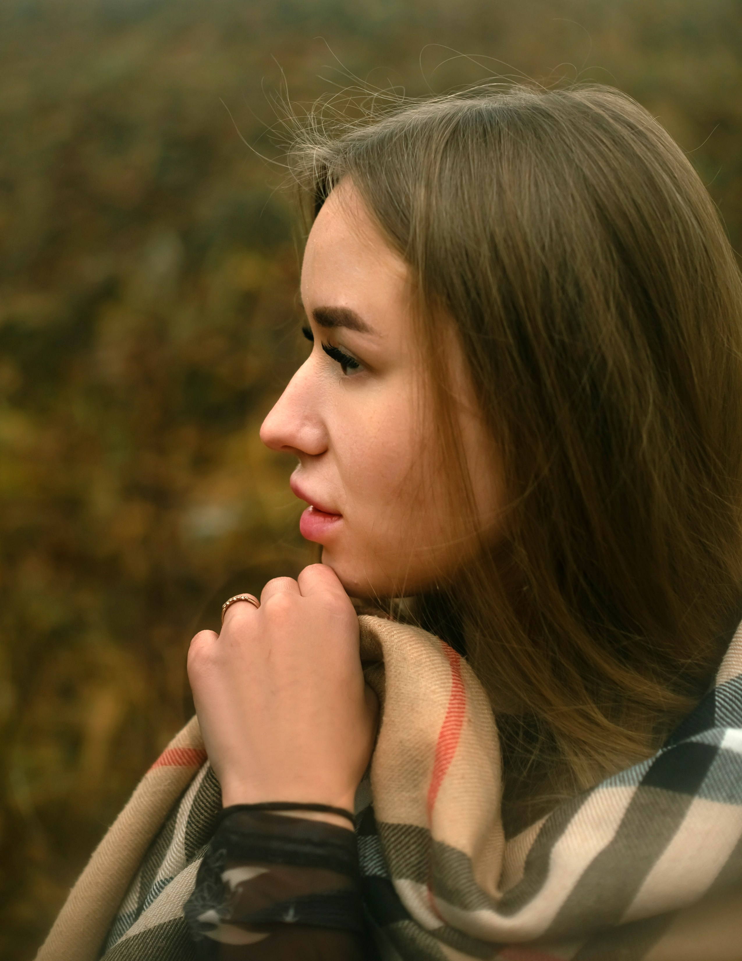 На фото портрет девушки в осеннем лесу в профиль.