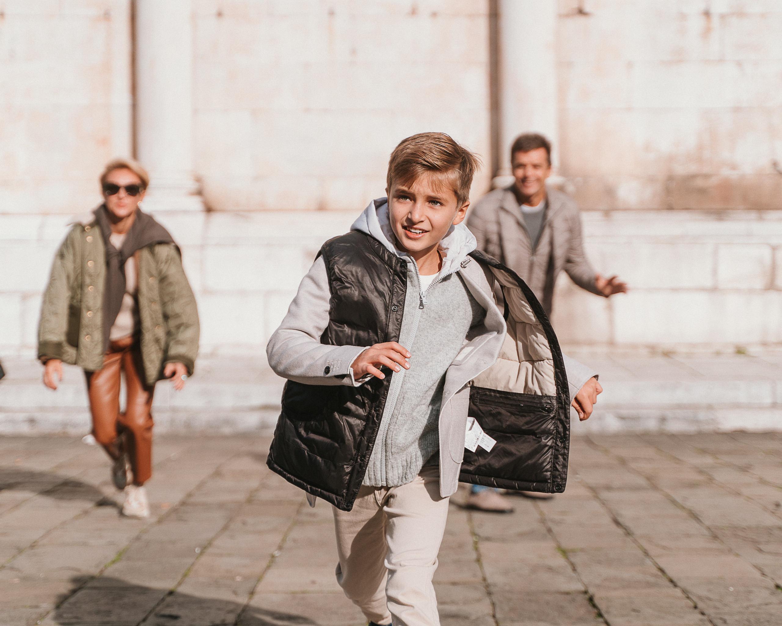 Smiling family members enjoying a sunny day while strolling through the old town of Lucca.