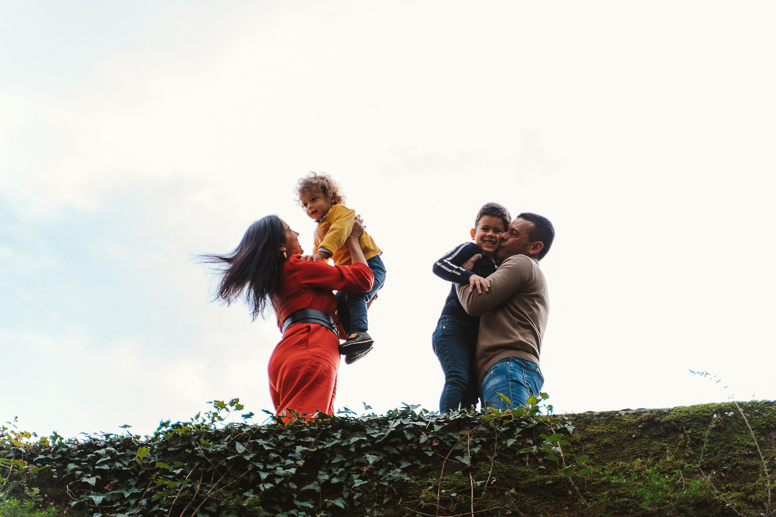 Parents embrace while their children play in a Tuscany forest.