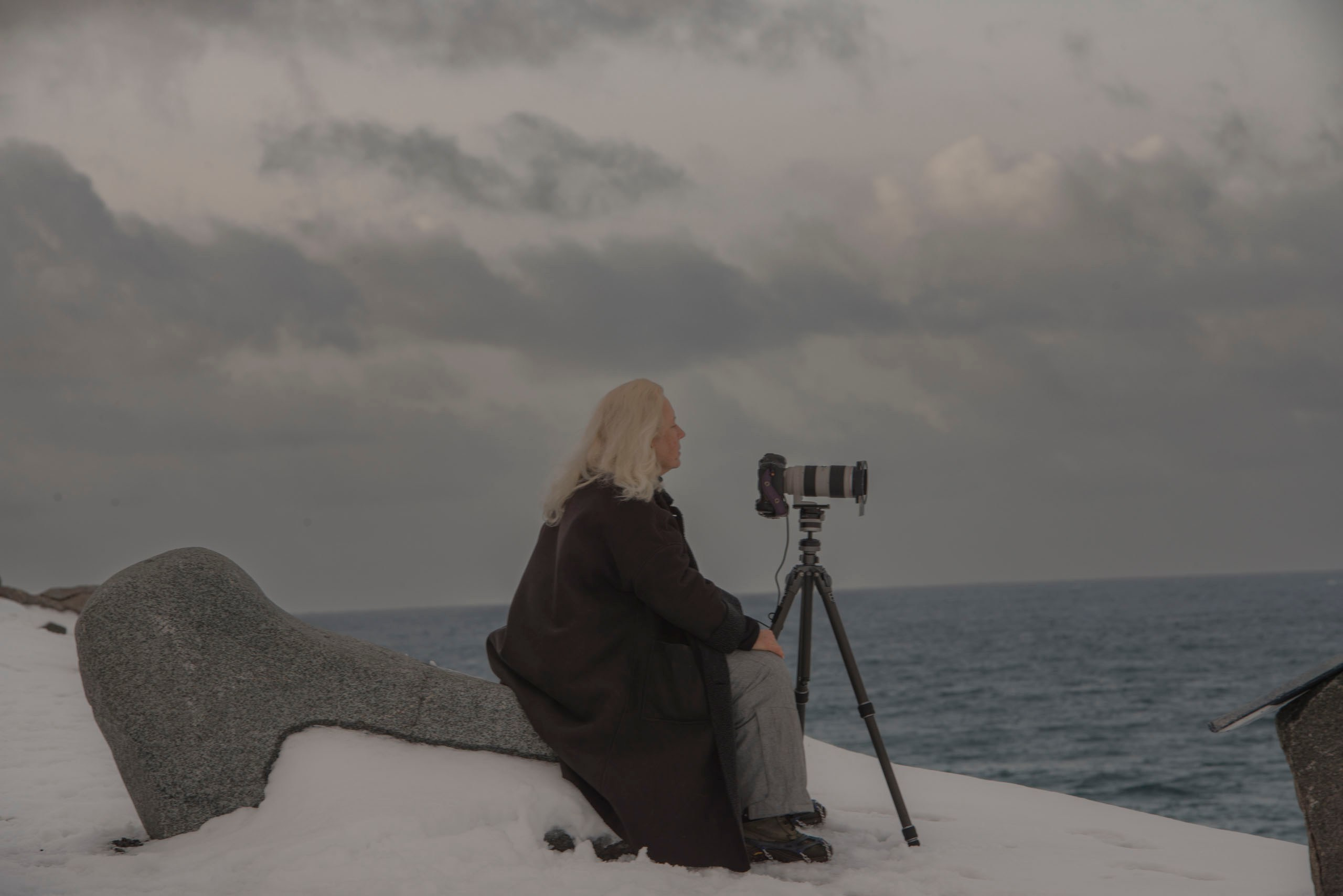 Photographer sitting by the Arctic ocean — наблюдение за северной природой и волнами.
