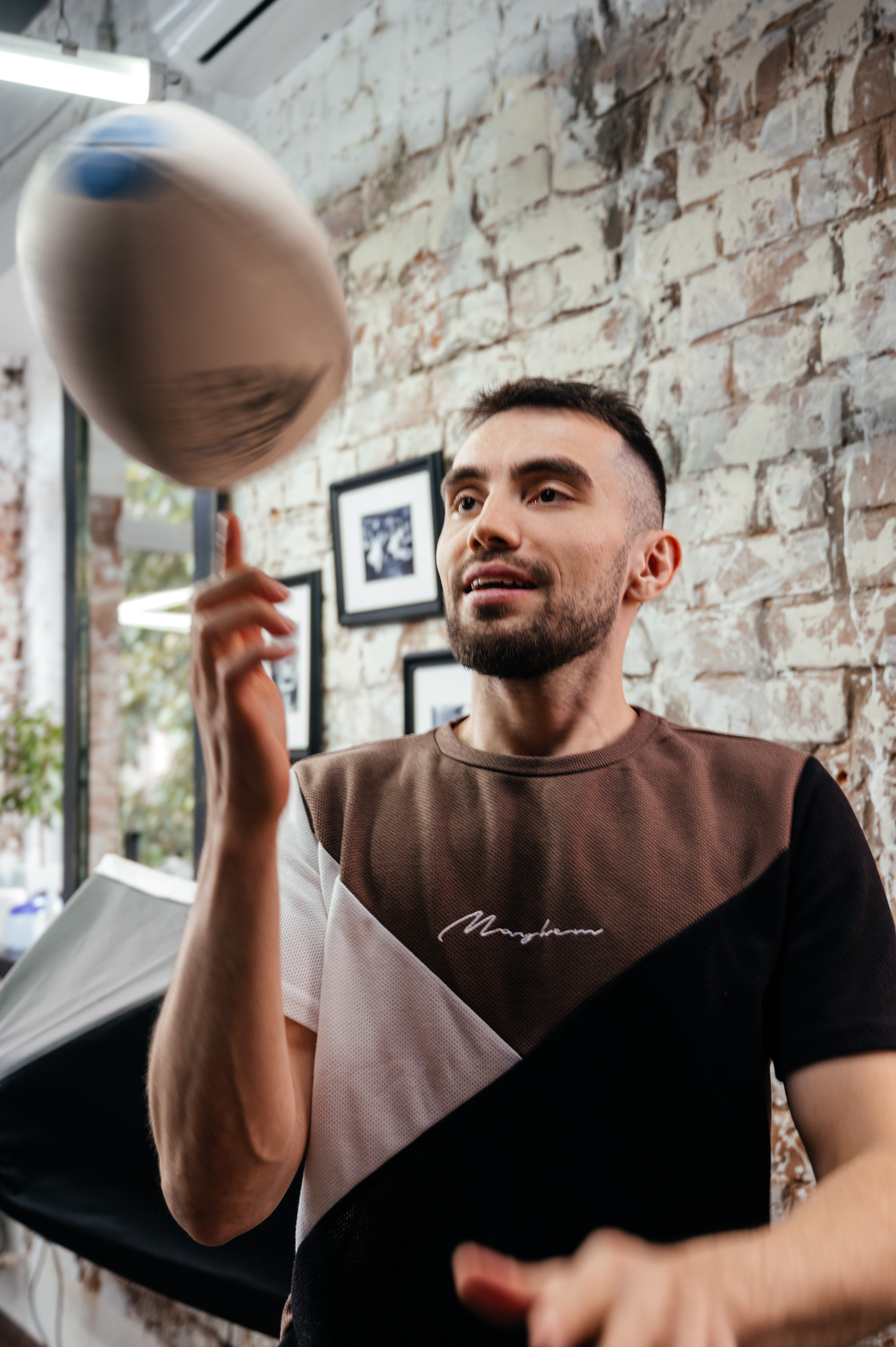 Парень в бербершопе, вертит на пальце мяч, для регби