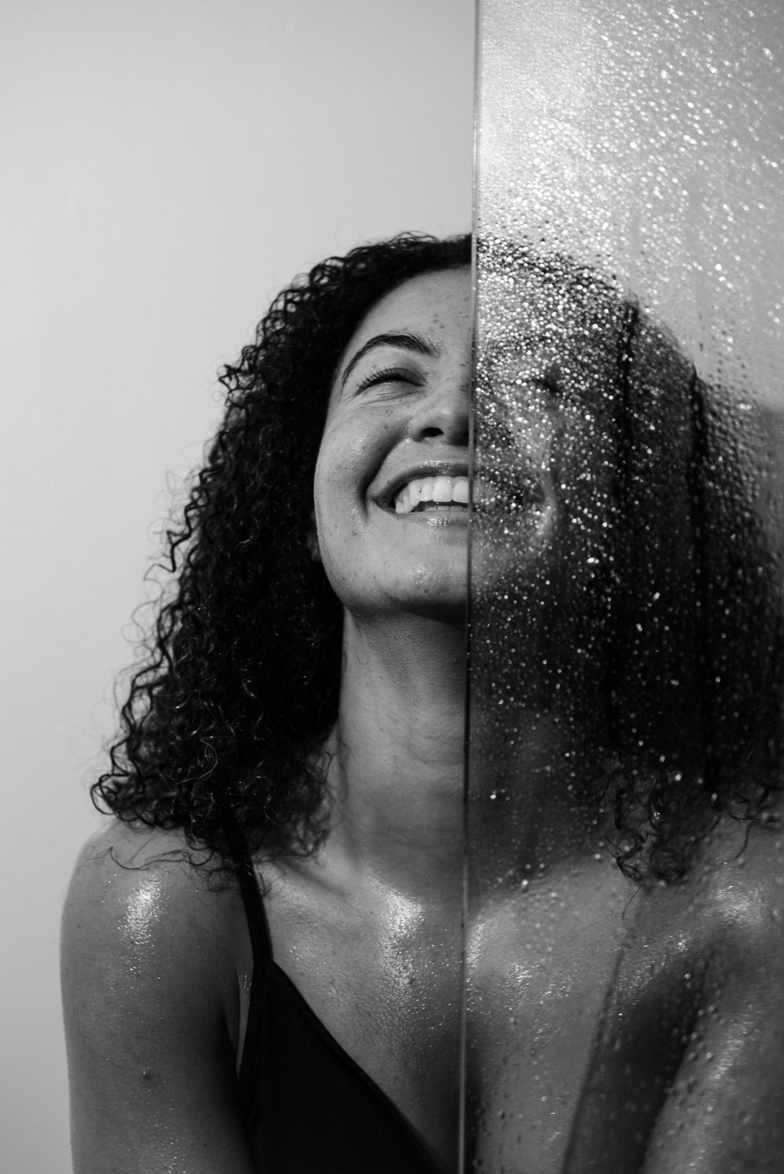 Empowering boudoir photography London — joyful portrait of topless woman with wet hair, free and playful energy