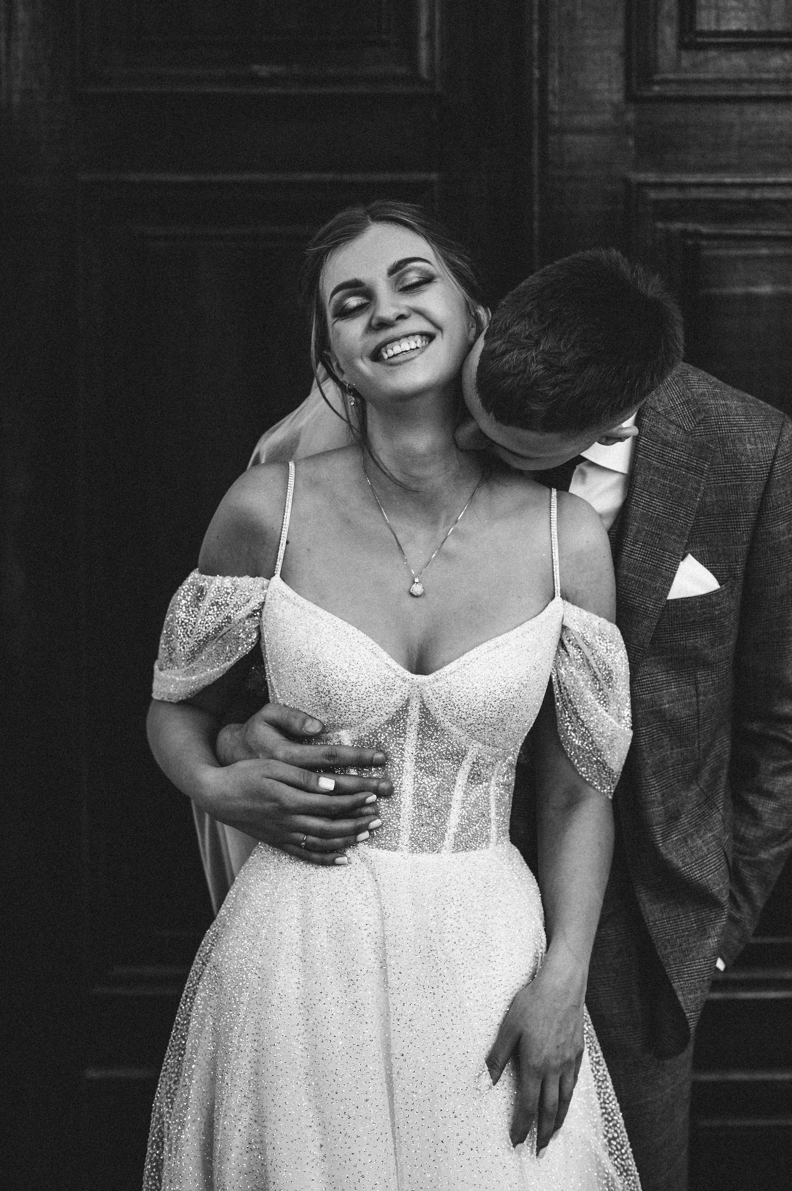 Черно-белая фотография жених целует невесту в шею