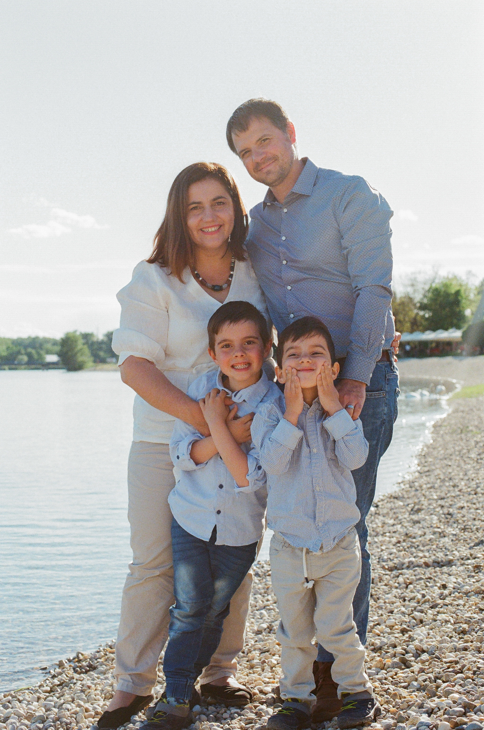 mother father and two sons being photographed on the beach