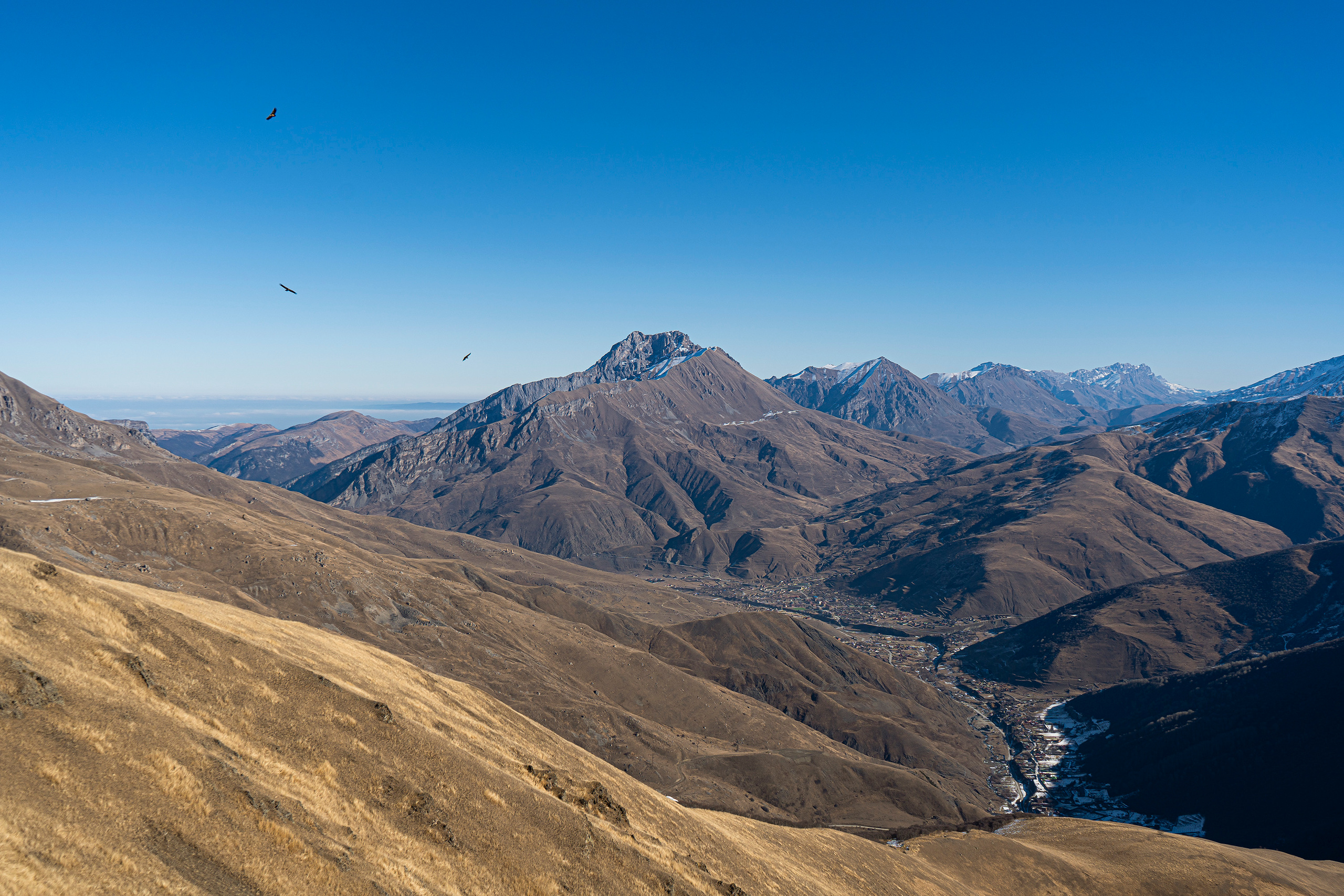 Вид на селение Фиагдон в Северной Осетии. Гора Тбау. Орлы парят над склонами гор