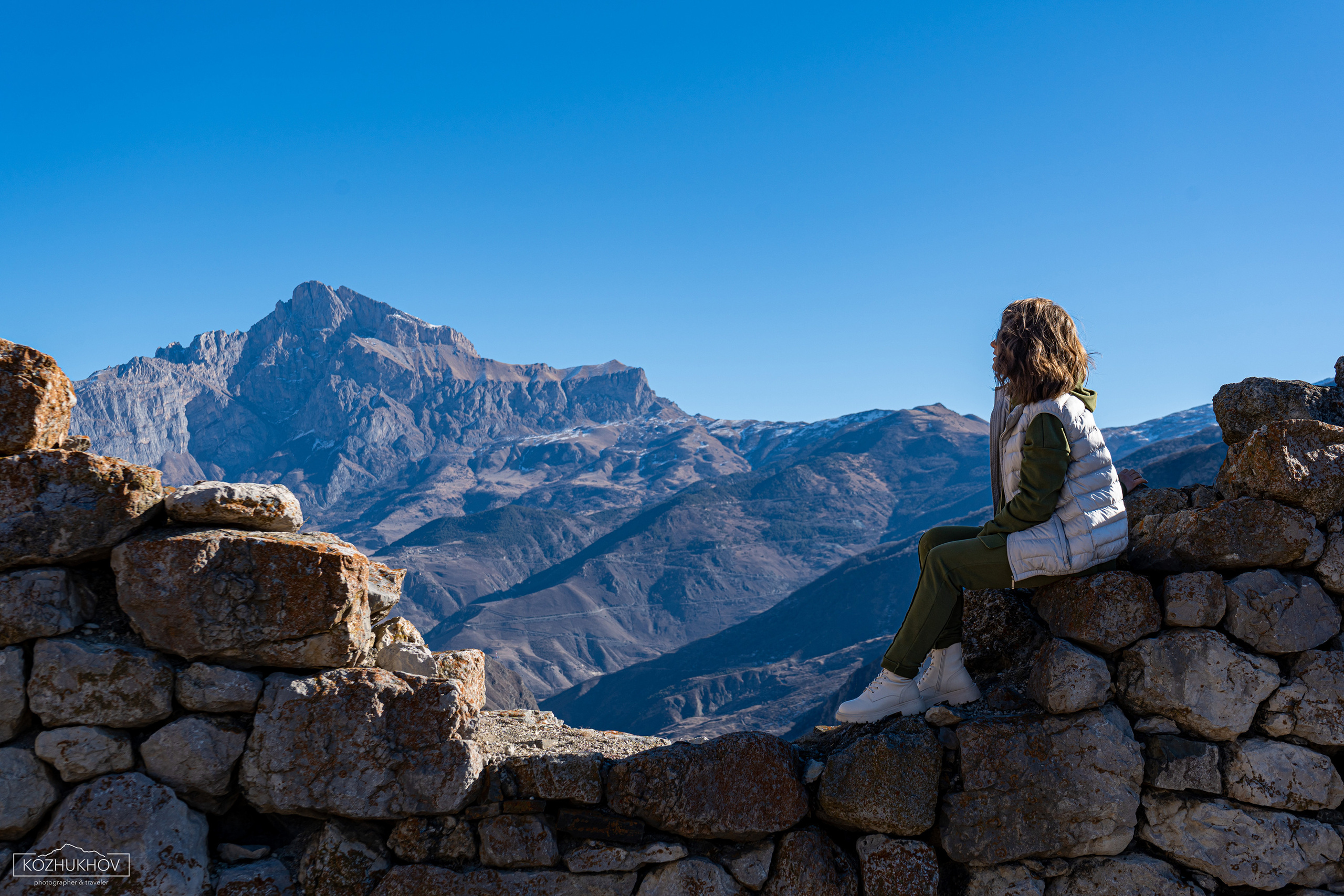 Девушка сидит на развалинах древней башни и любуется горой Кариухох. Вид с Верхнего Мизура
