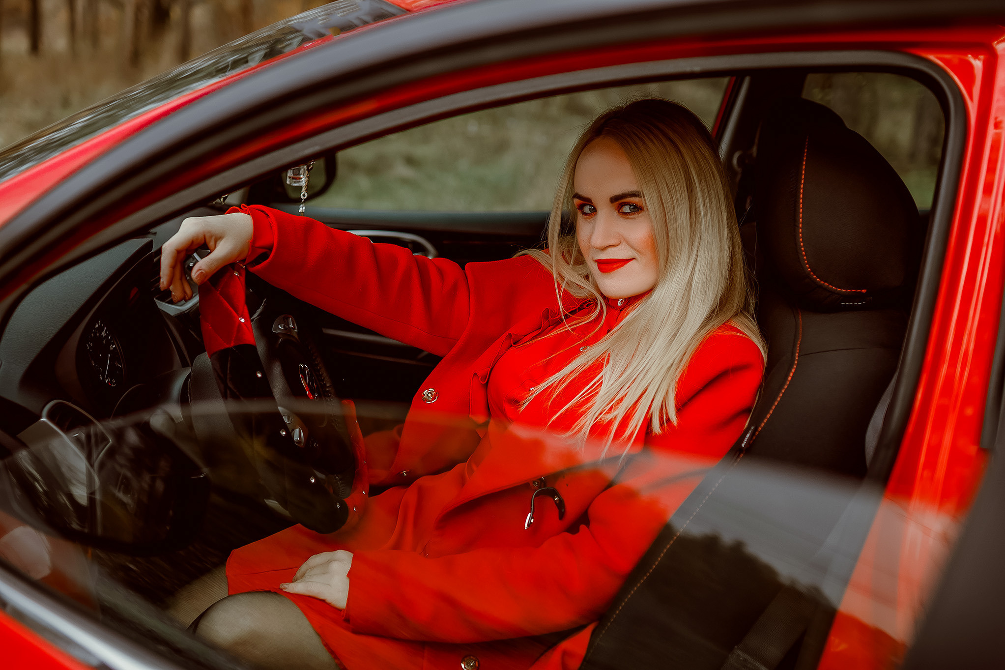 Блондинка в красном пальто и в красной машине.