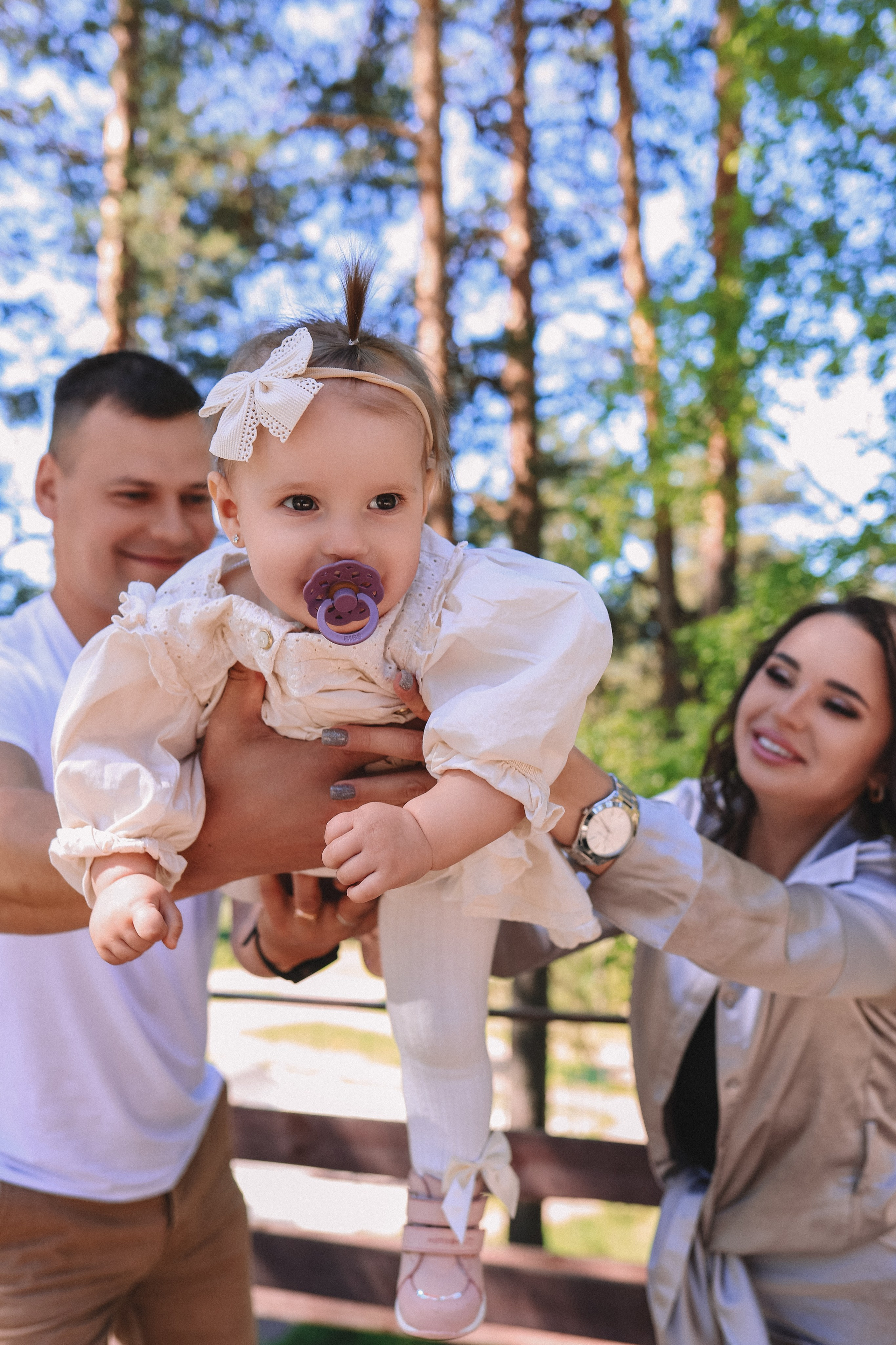 Папа и мама поднимают малыша, семейная съёмка на природе