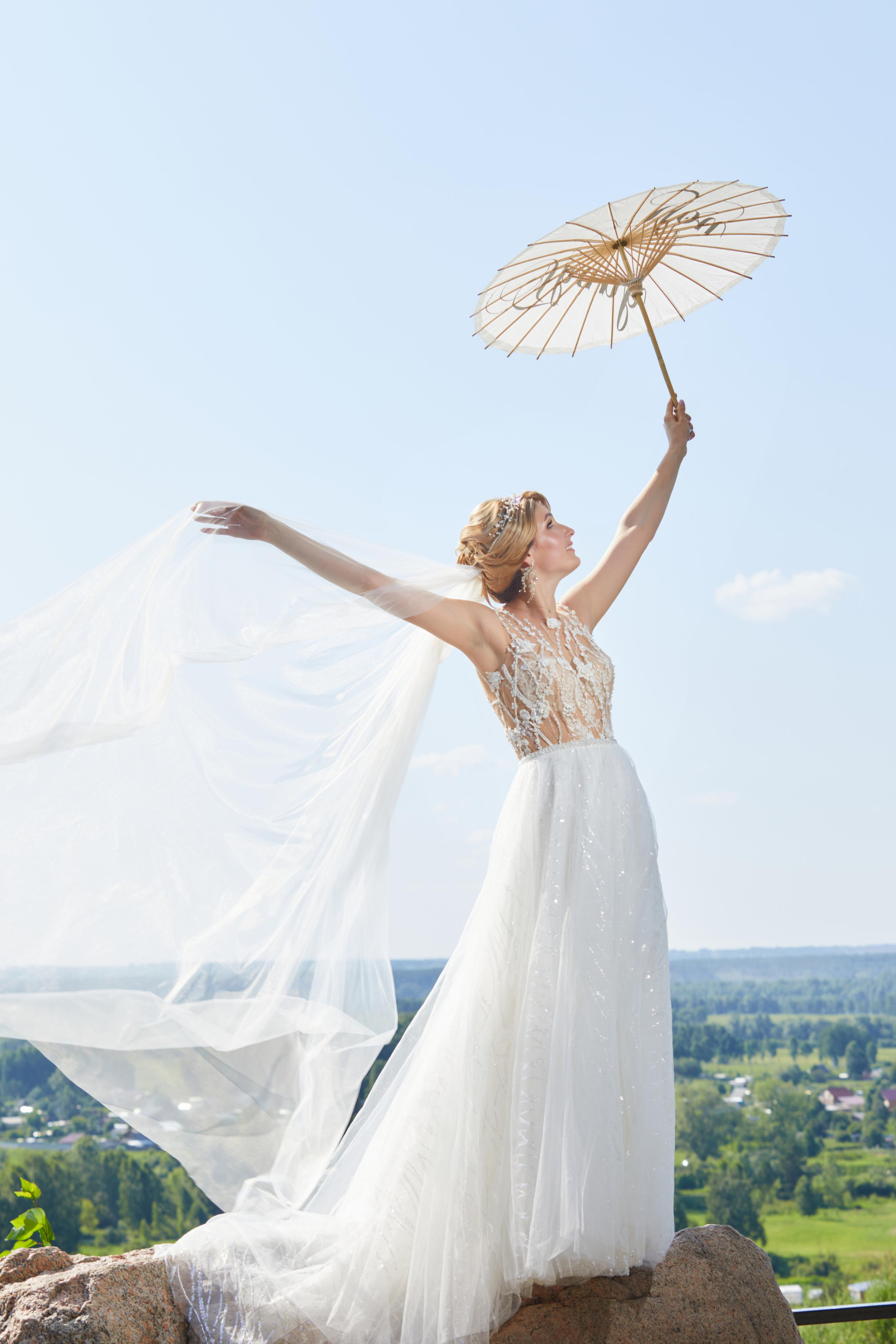 Невеста поднимает вверх свадебный зонт
