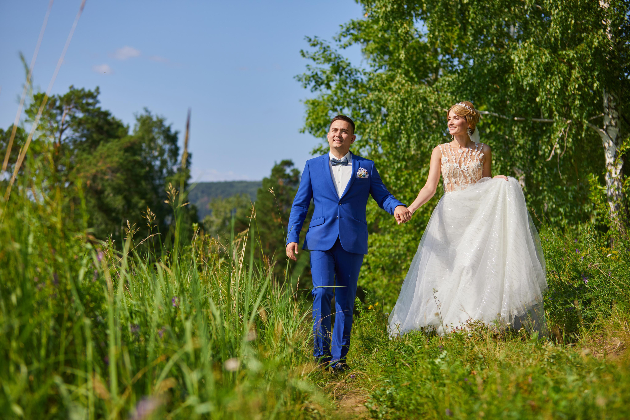 Жених и невеста идут под руку по лесной тропинке