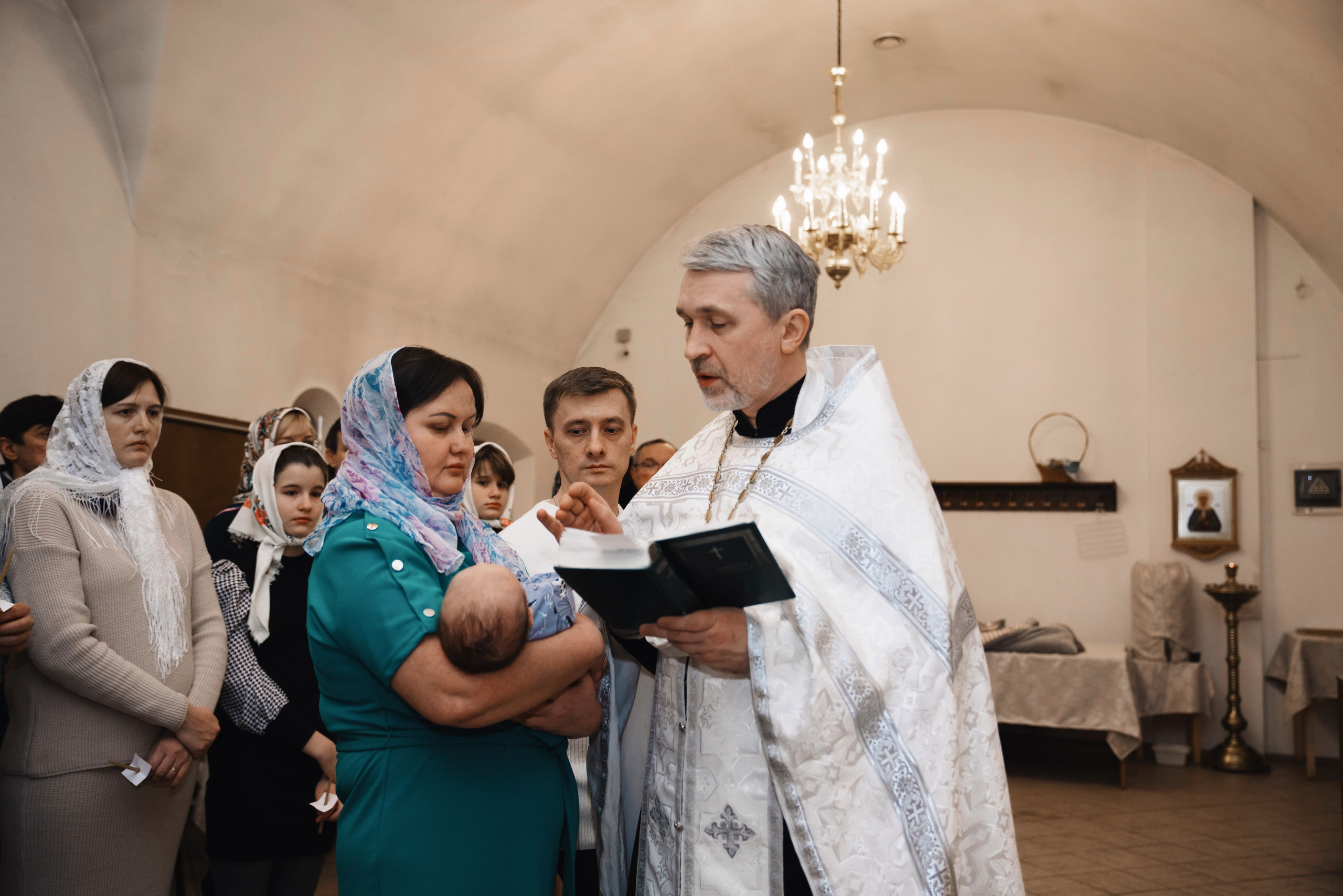 священник читает молитву на крещении