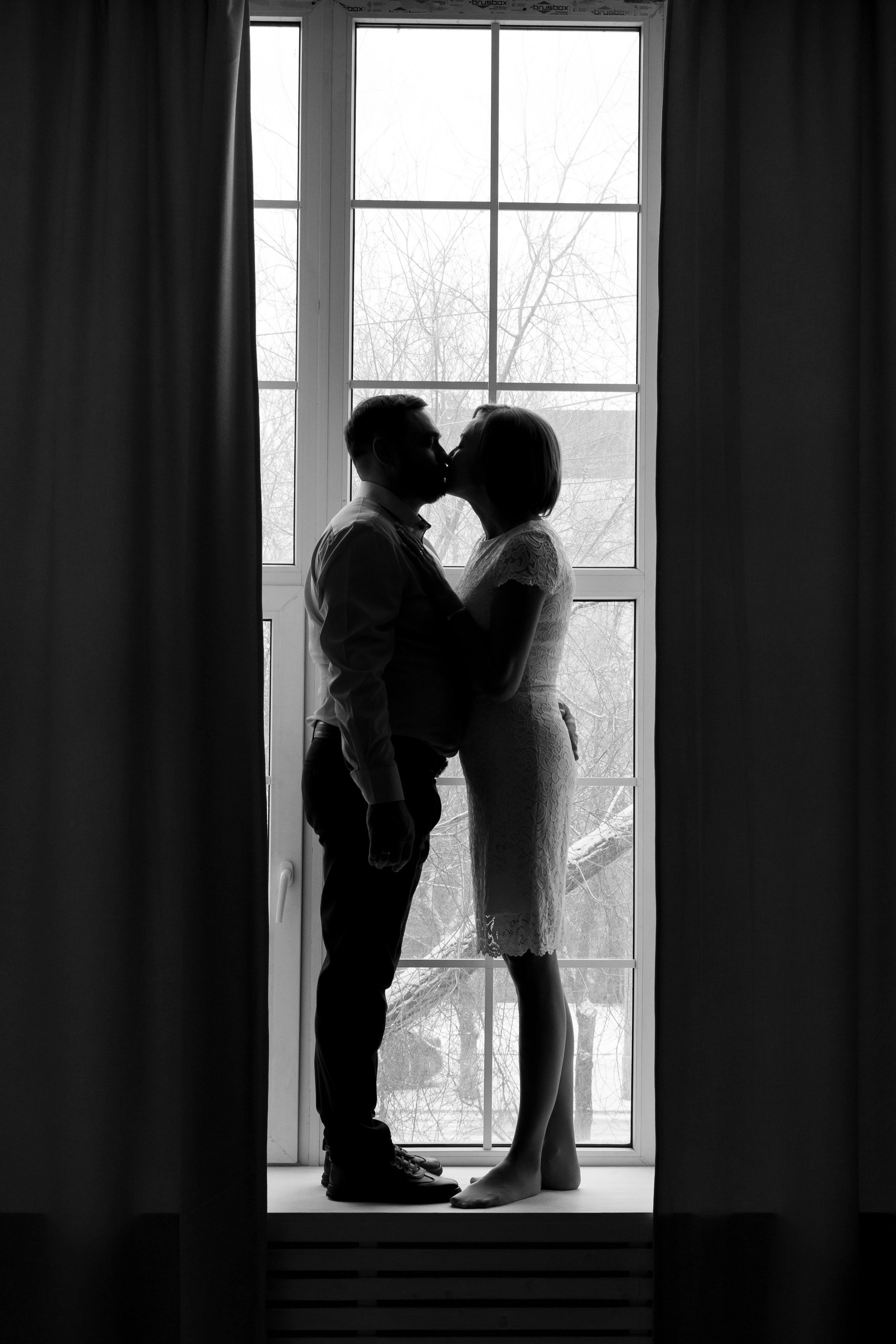Жених и невеста целуются, стоя на подоконнике. Свадебная фотосессия Астрахань.