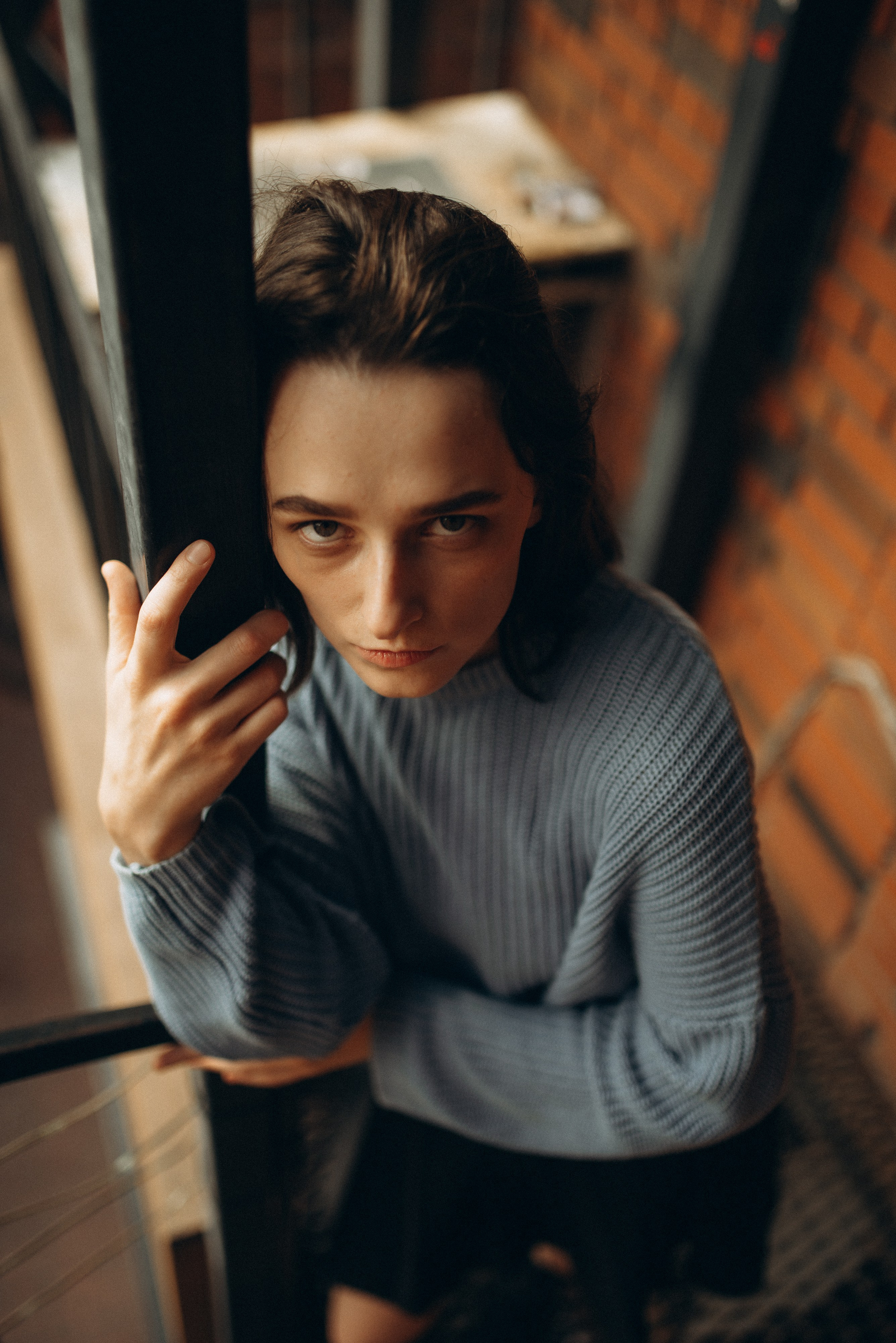 Девушка в голубом свитере на фоне кирпичной стены и черной винтовой лестницы, портретная фотосессия в индустриальном стиле. Фотосессия в Новосибирске. 2.